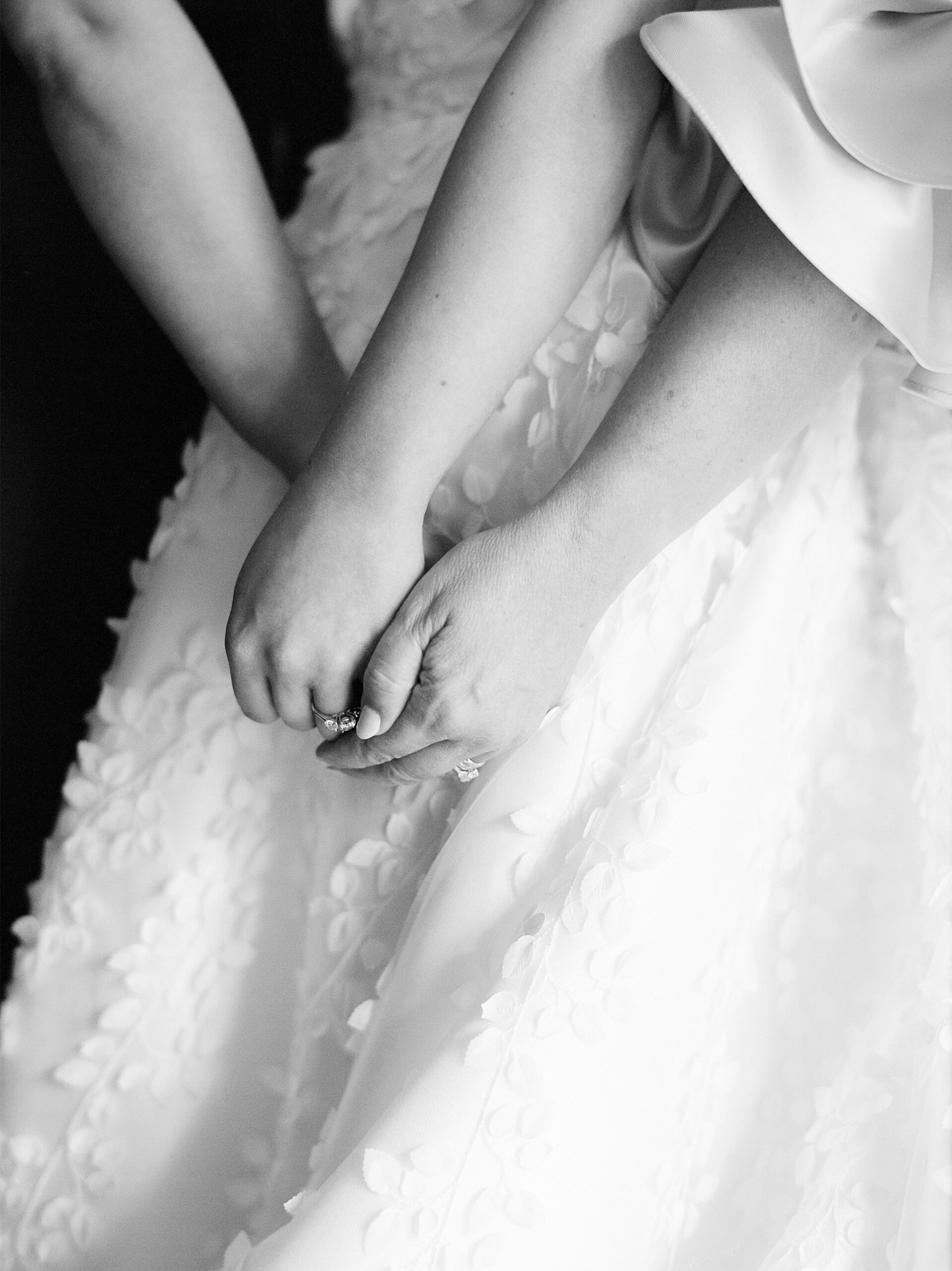 bride holds mom's hand on top of textured skirt of Anne Barge wedding dress