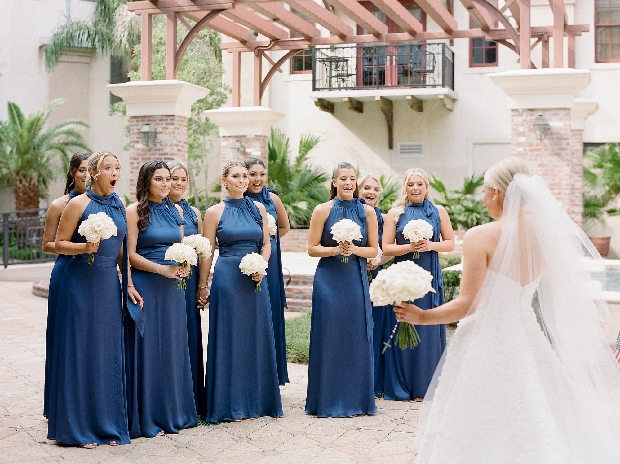 bride faces bridesmaids in blue gowns for first look before Louisiana wedding 