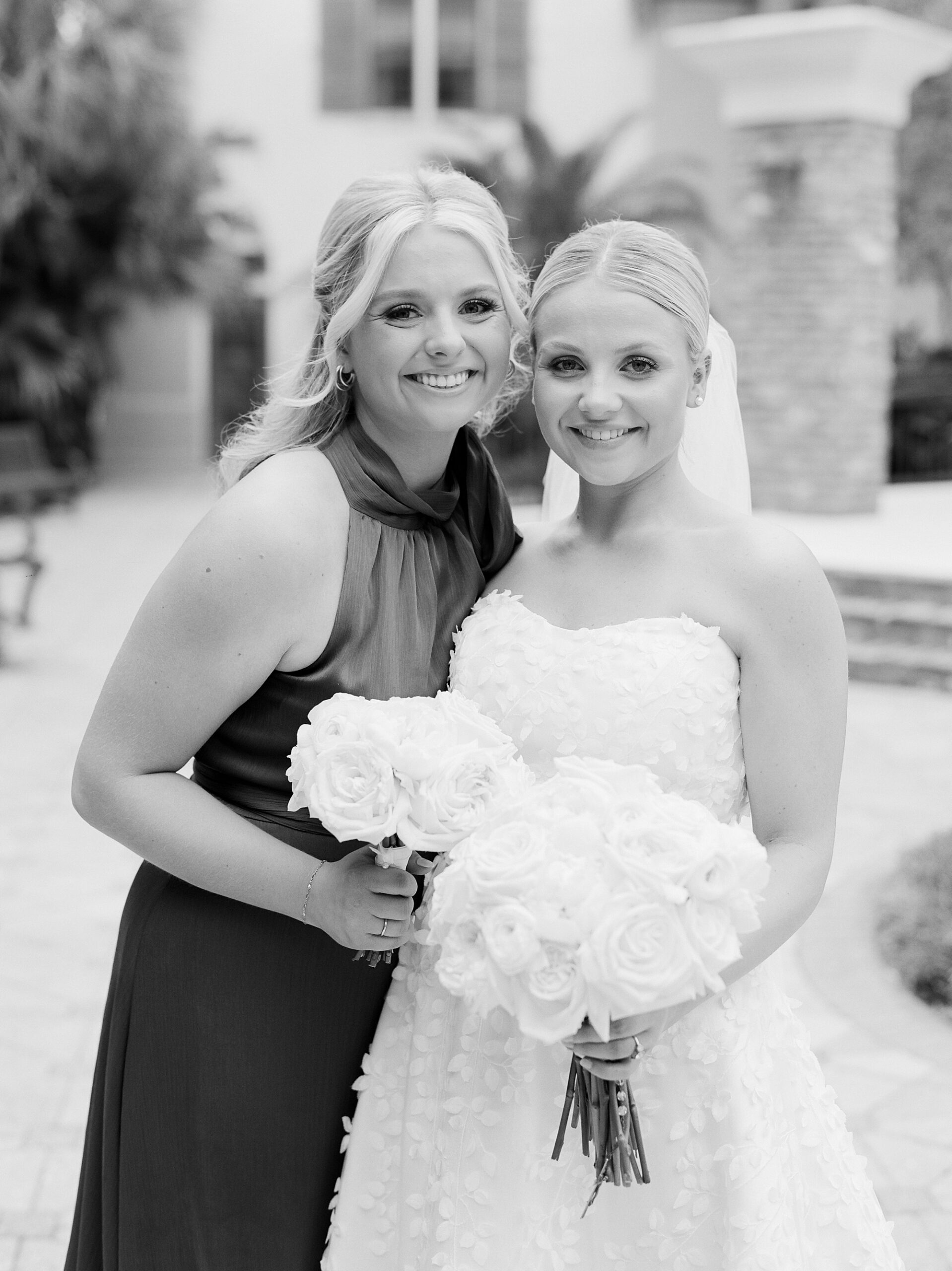 bride hugs bridesmaid while holding bouquet of white flowers 
