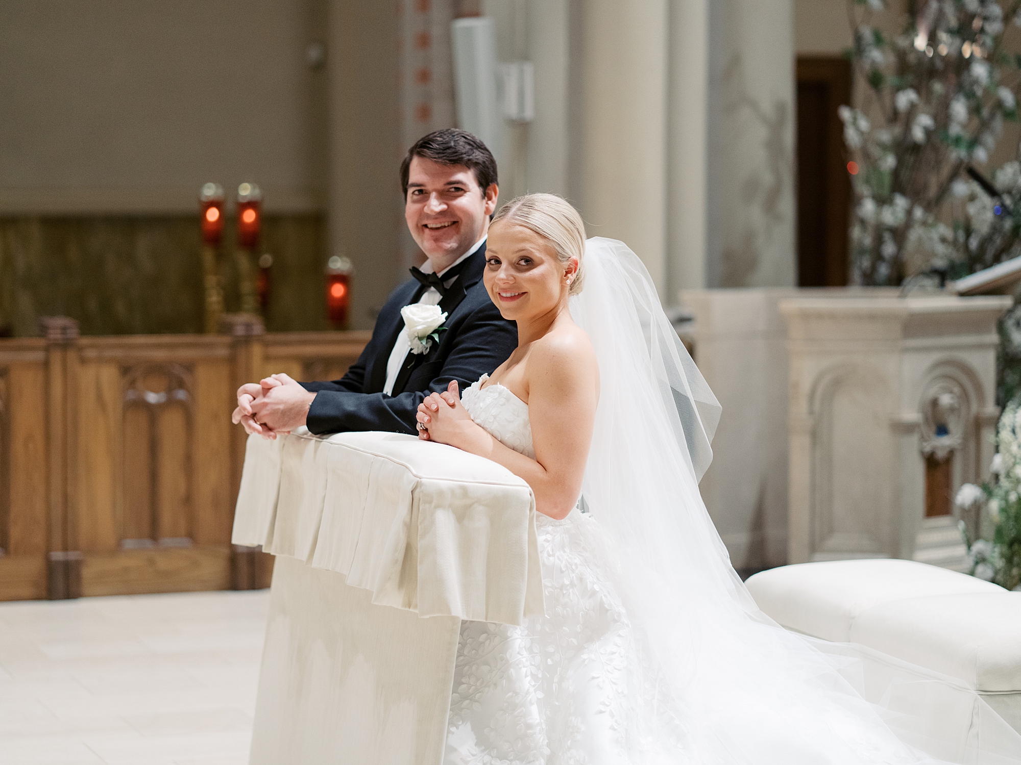bride and groom kneel at alter during traditional Catholic Church wedding at St. John Cathedral