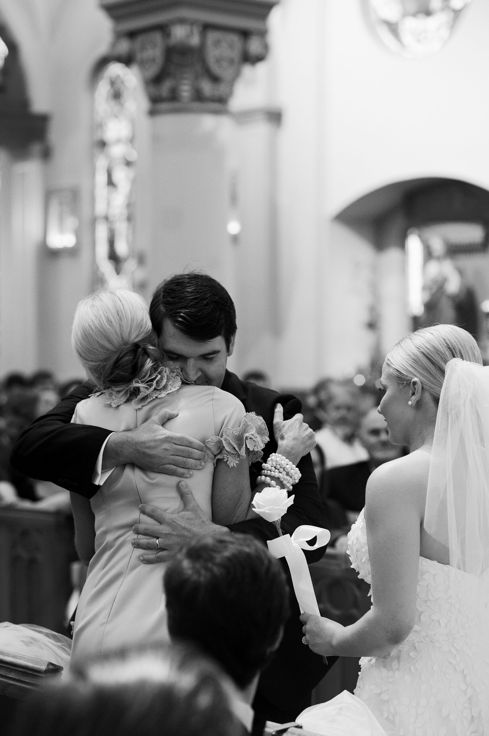 groom hugs mother during traditional Catholic Church wedding at St. John Cathedral