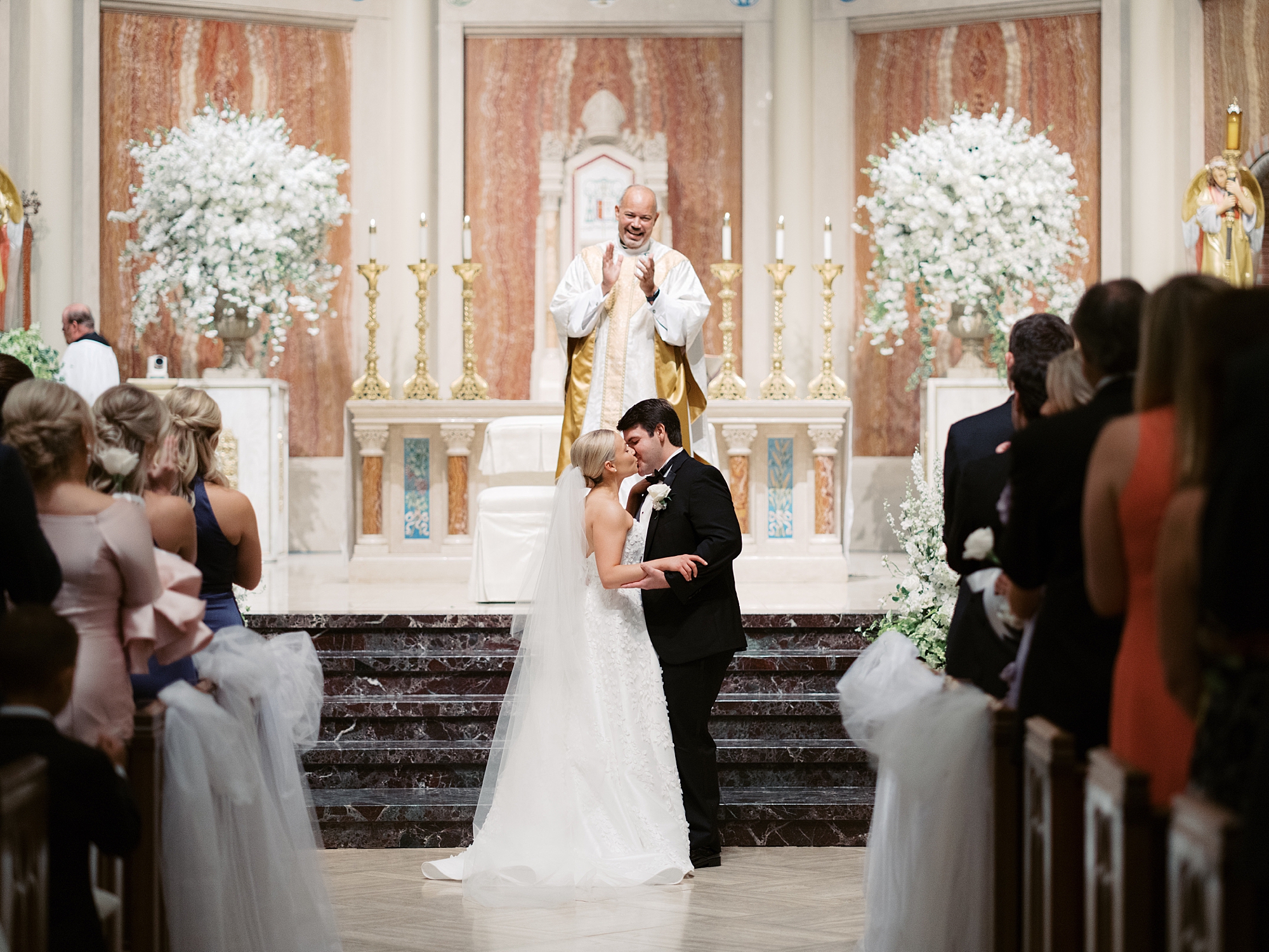newlyweds kiss at alter after traditional Catholic Church wedding at St. John Cathedral