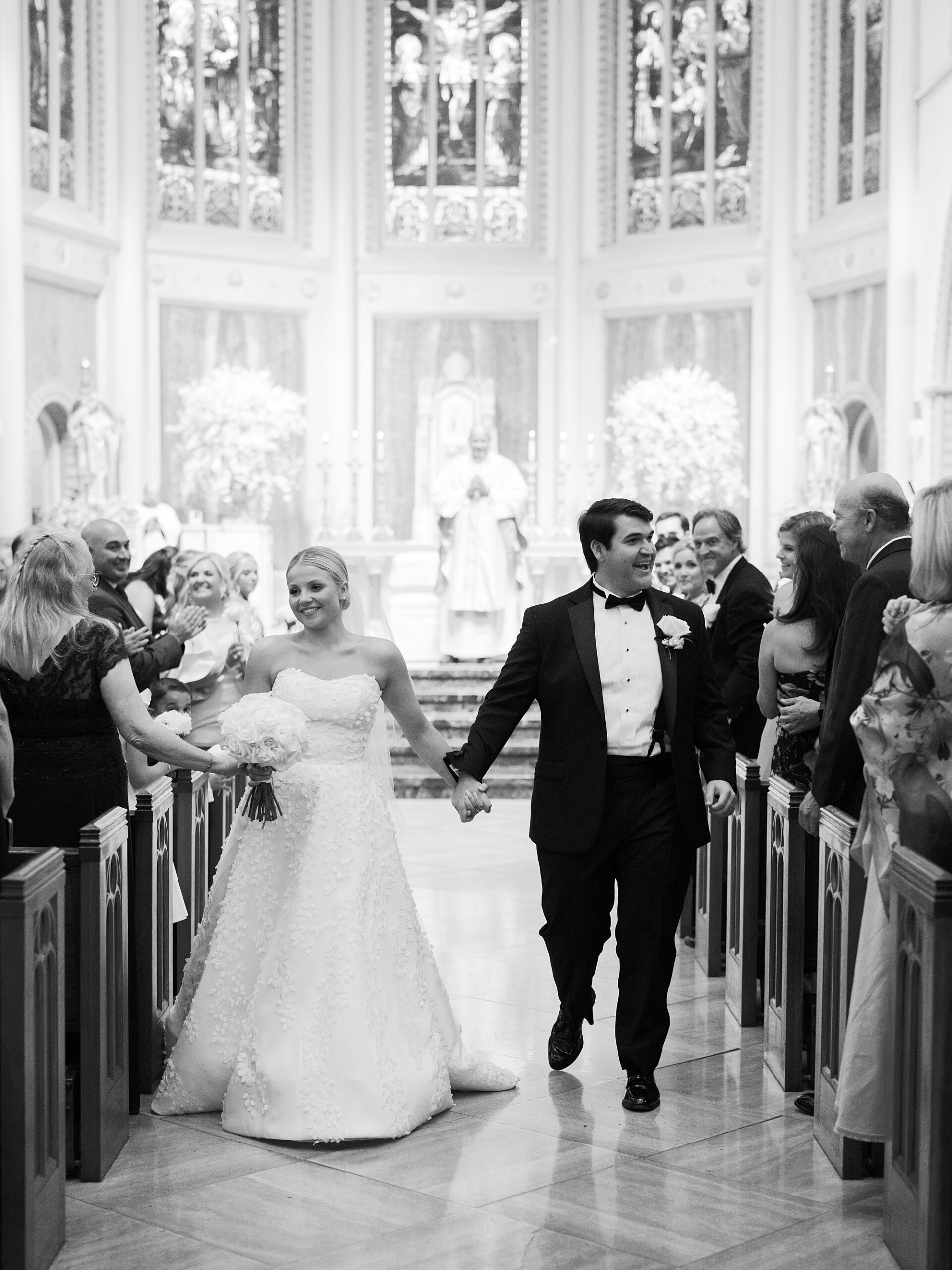 bride and groom greet guests during recessional after traditional Catholic Church wedding at St. John Cathedral