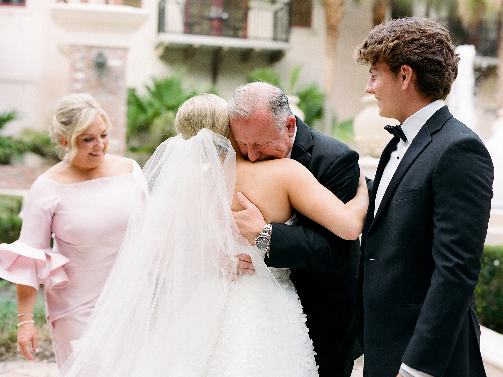 bride and father hug on patio during first look on Louisiana wedding day