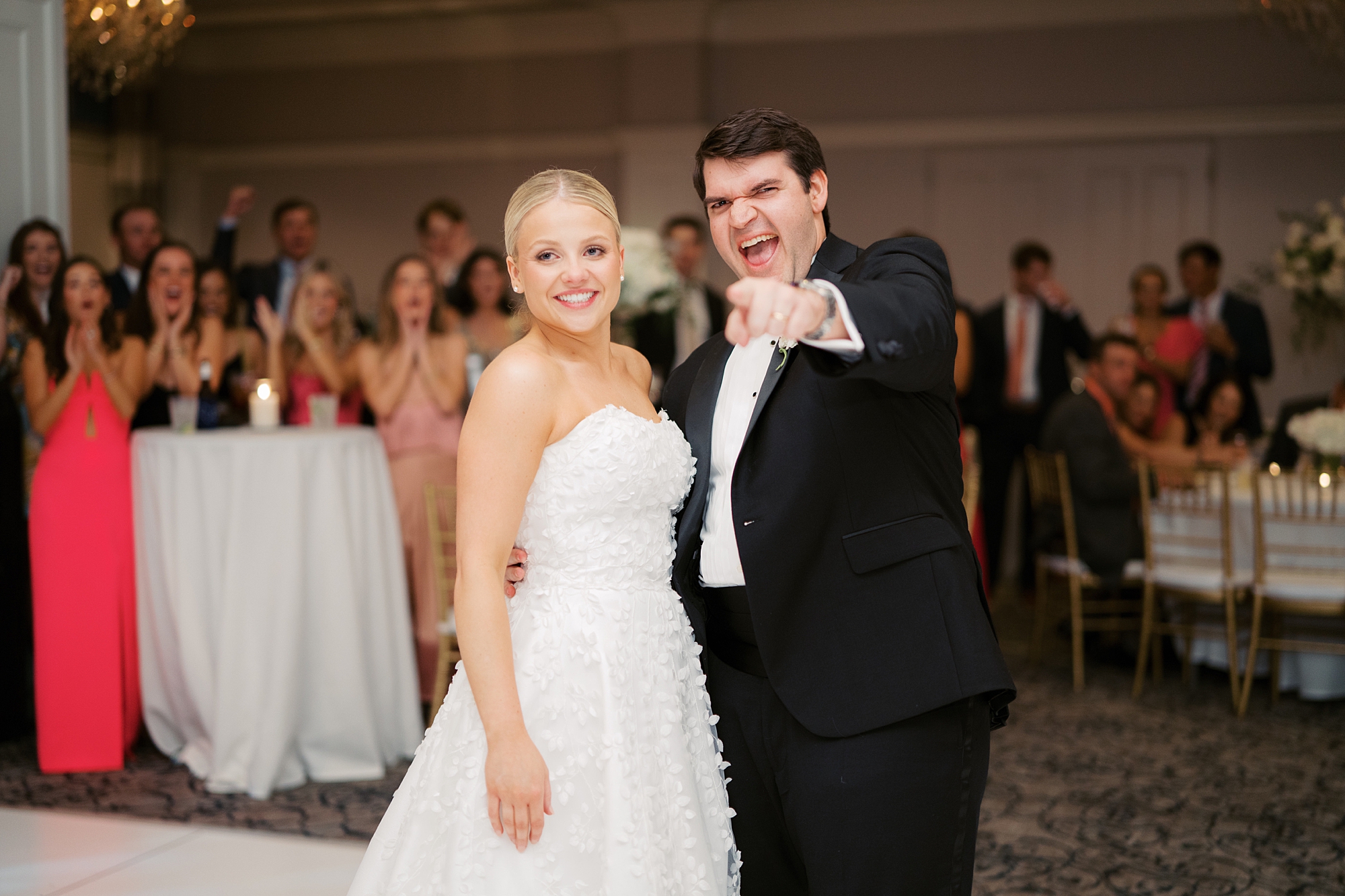 bride and groom pose on dance floor smiling for guests 