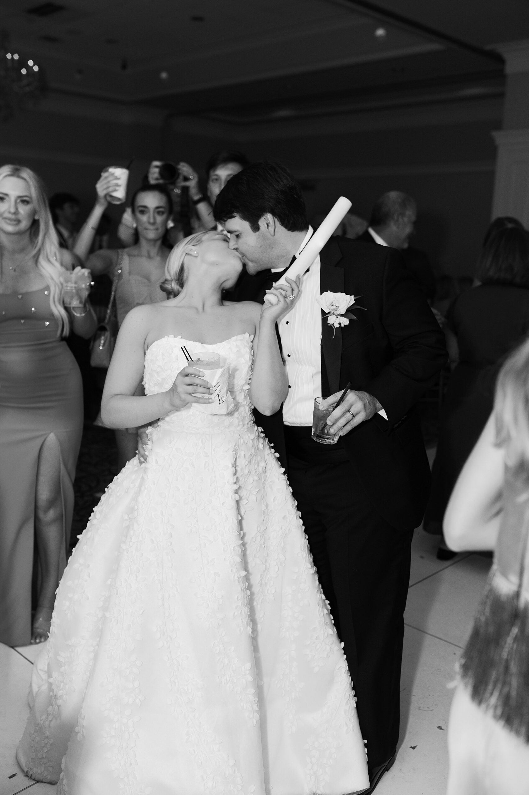 bride holds glow stick leaning back to kiss groom on dance floor 