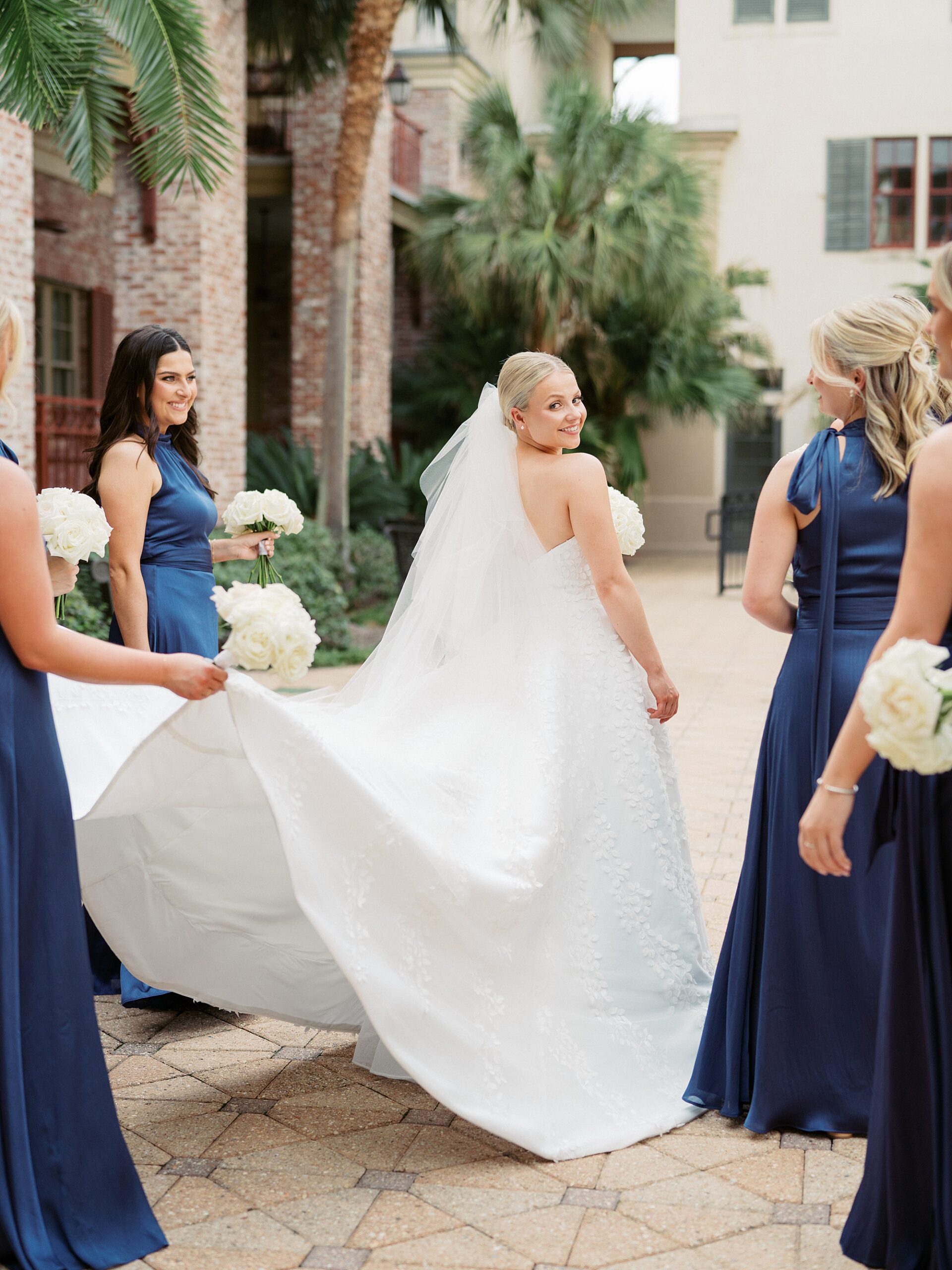 bridesmaid holds up back of wedding dress for bride 