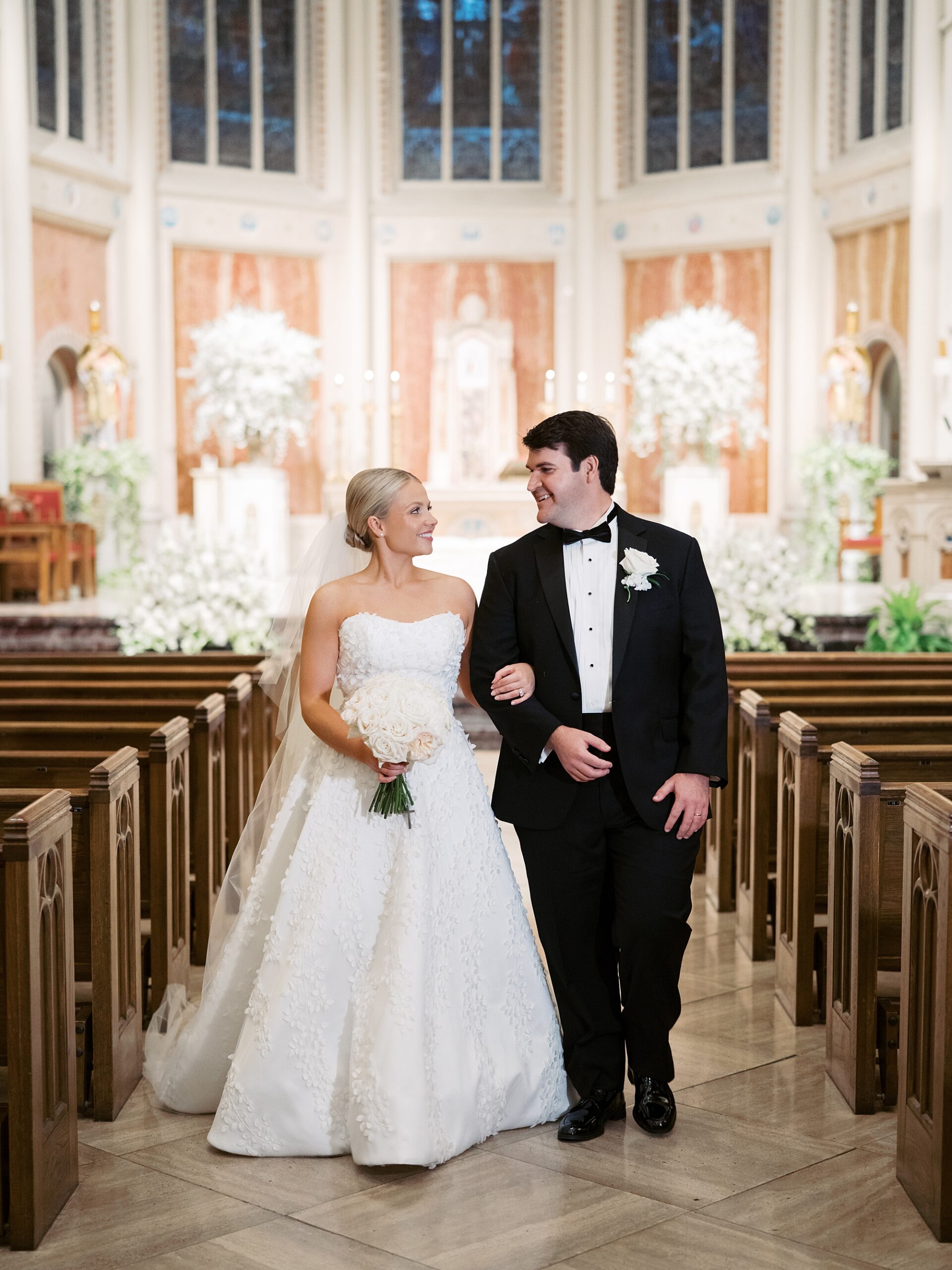 bride and groom stand between pews inside St. John's Cathedral 