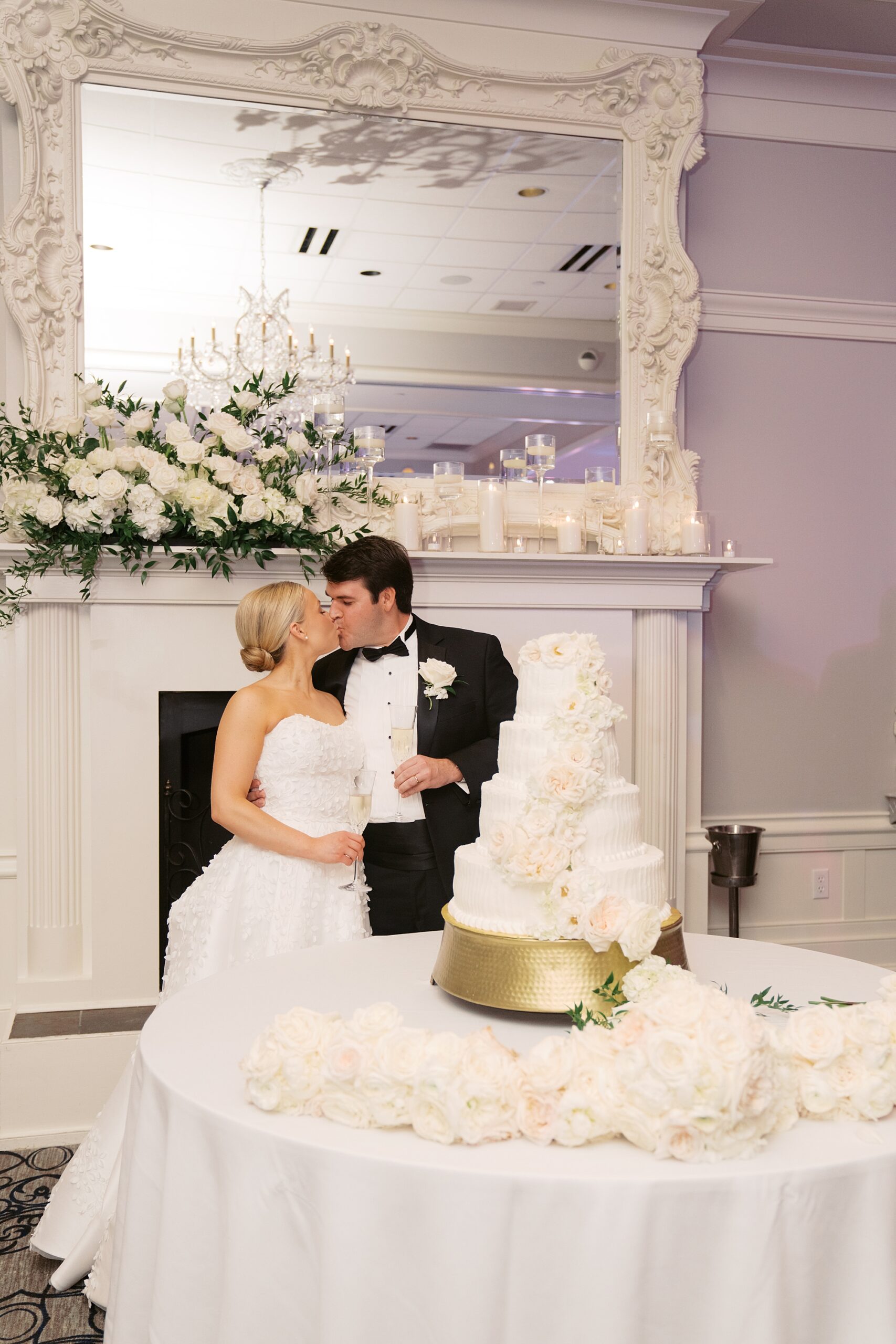 newlyweds kiss while cutting tiered wedding cake during wedding reception in Lafayette LA
