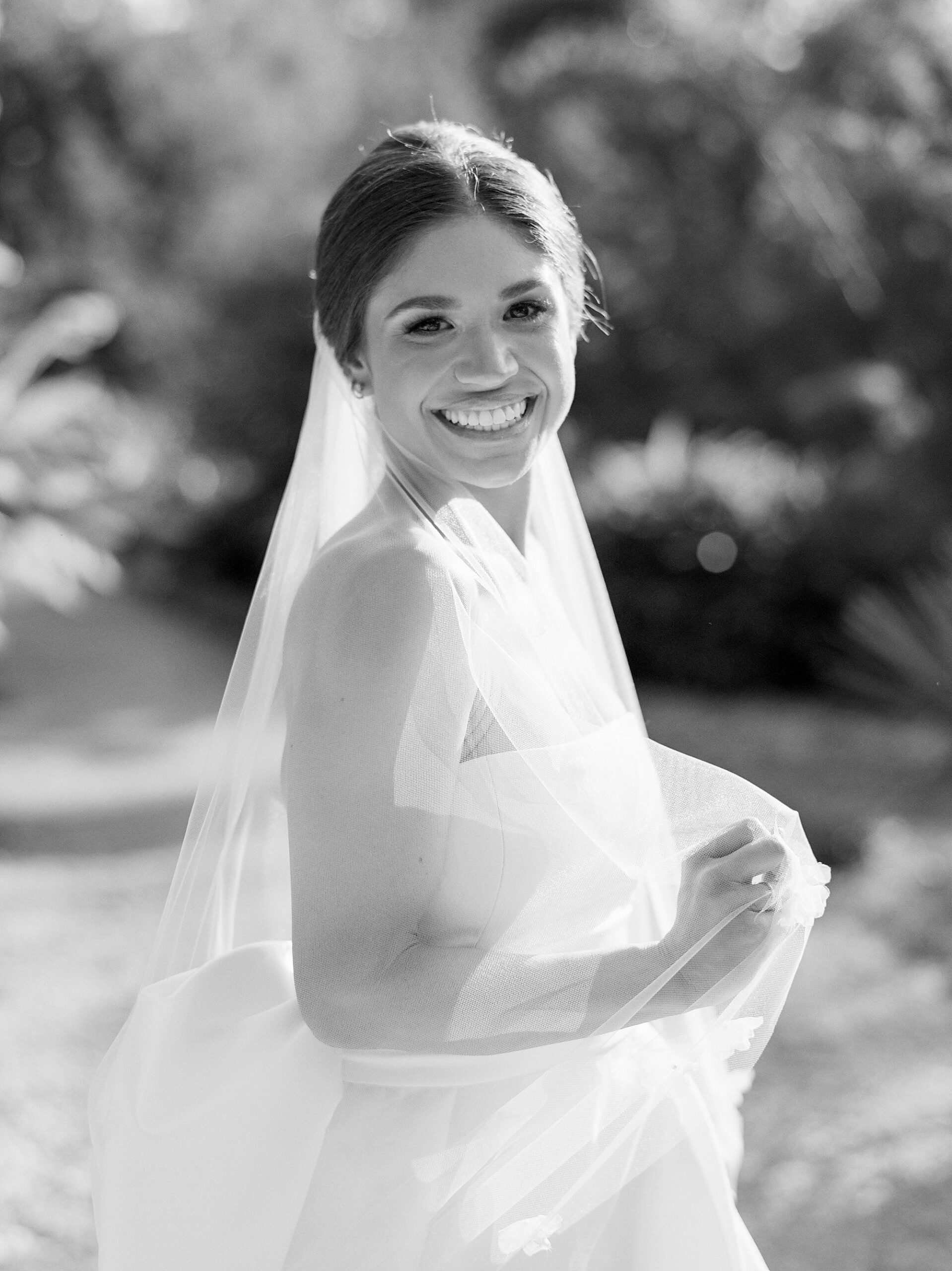 bride holds veil and turns to smile at camera on Jefferson Island