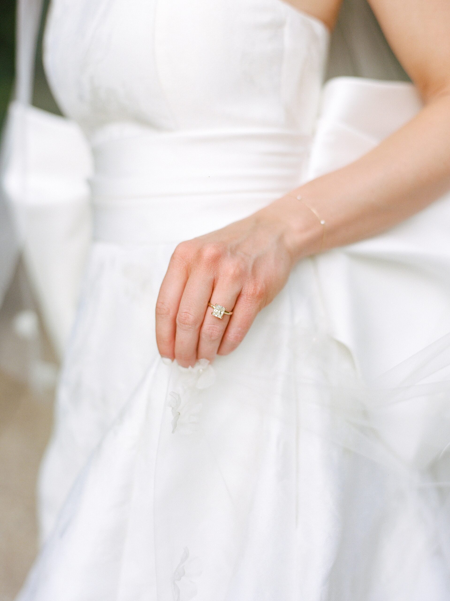 bride lifts up skirt showing off engagement ring during Rip Van Winkle gardens bridal portraits 