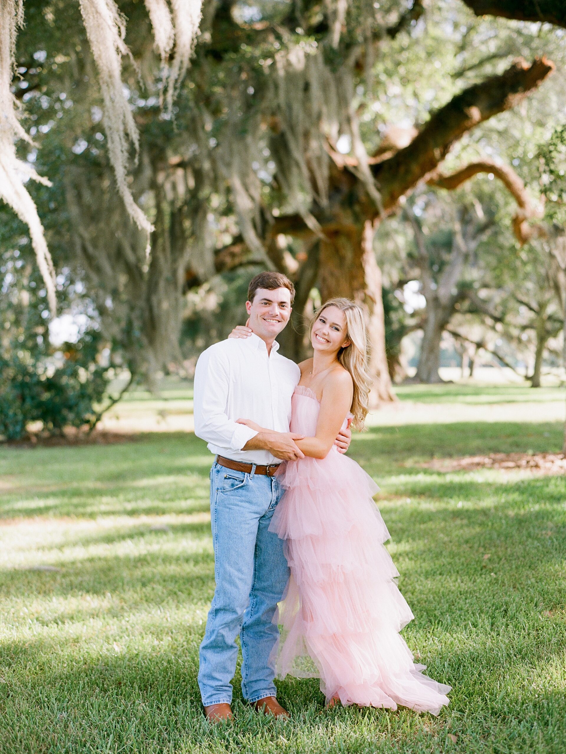 engaged couple hugs under trees at Sacred Heart of Grand Coteau