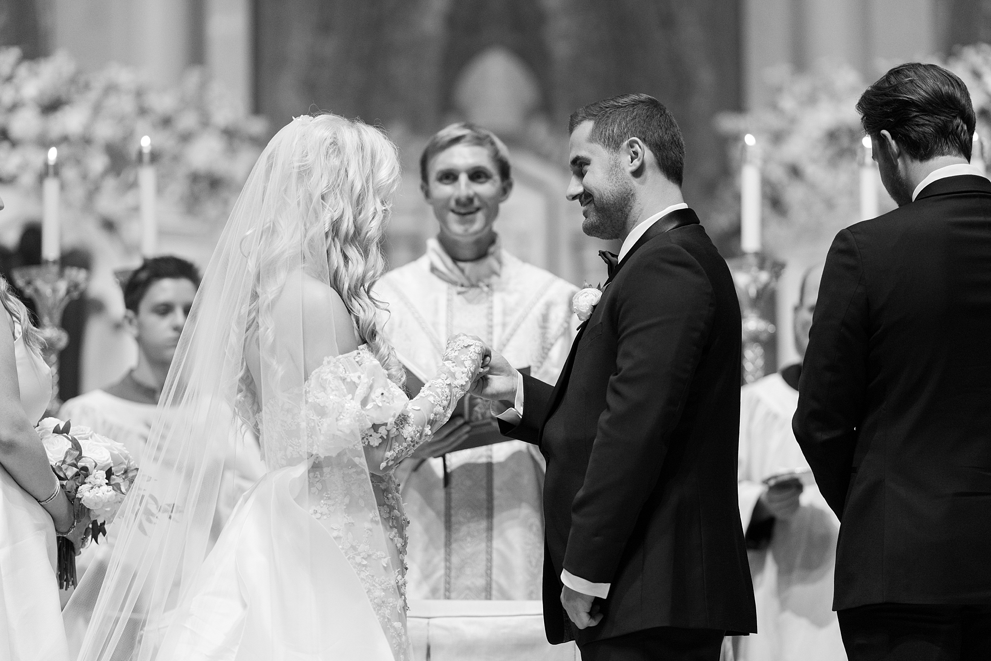 newlyweds hold hands during Cathedral Of St. John during traditional Catholic wedding ceremony