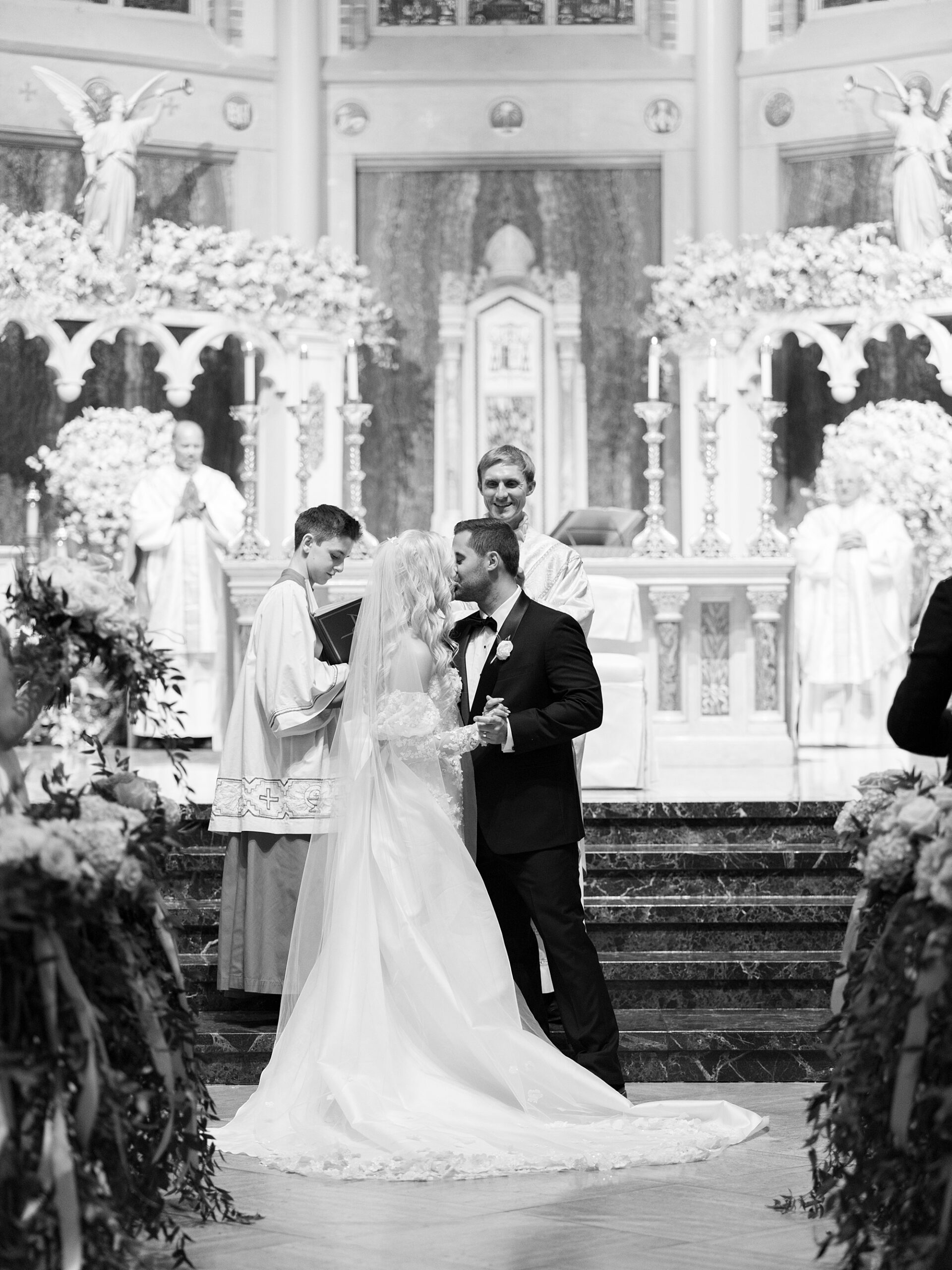 bride and groom kiss during Cathedral Of St. John during traditional Catholic wedding ceremony