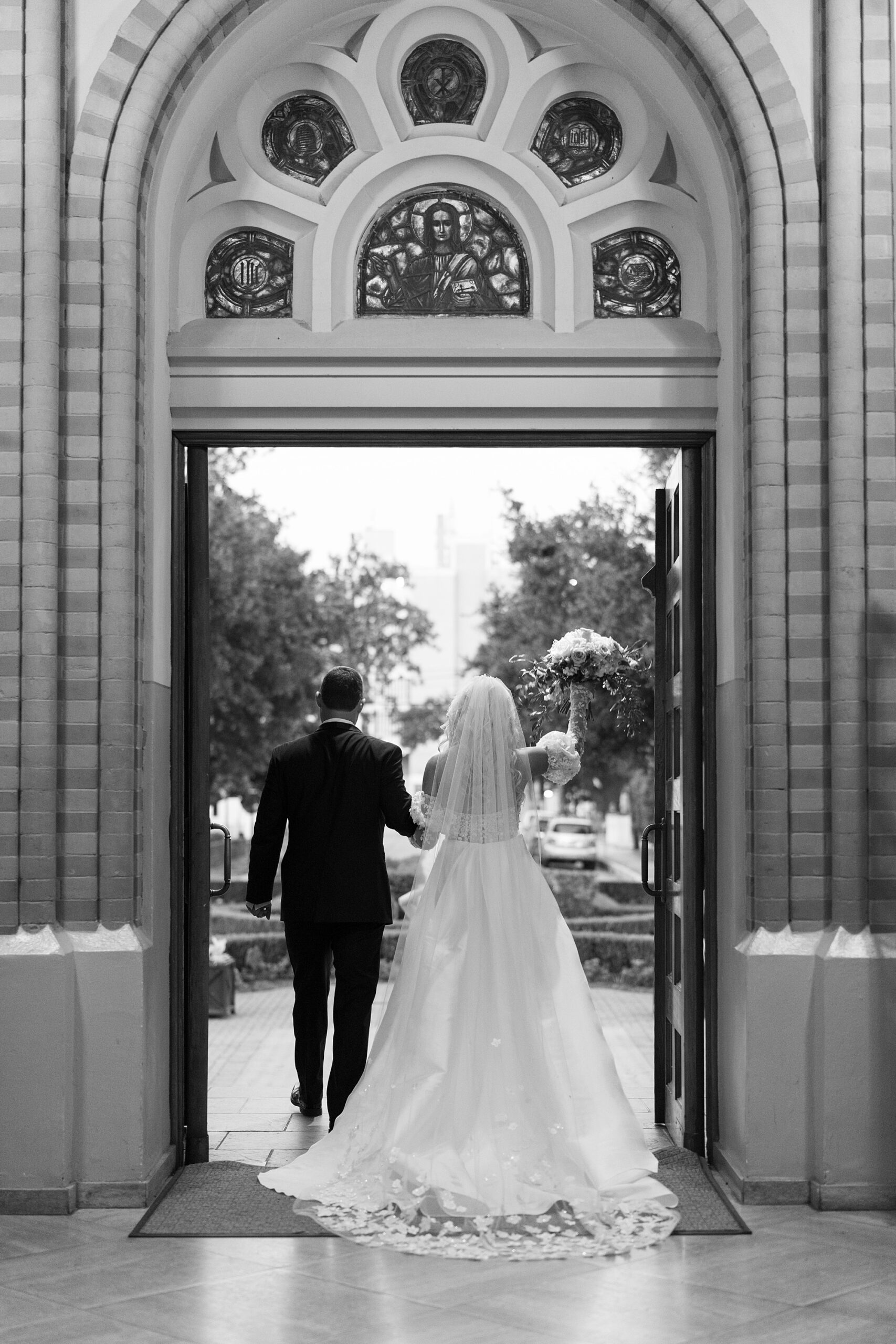 newlyweds hold hands walking out doors at Cathedral Of St. John