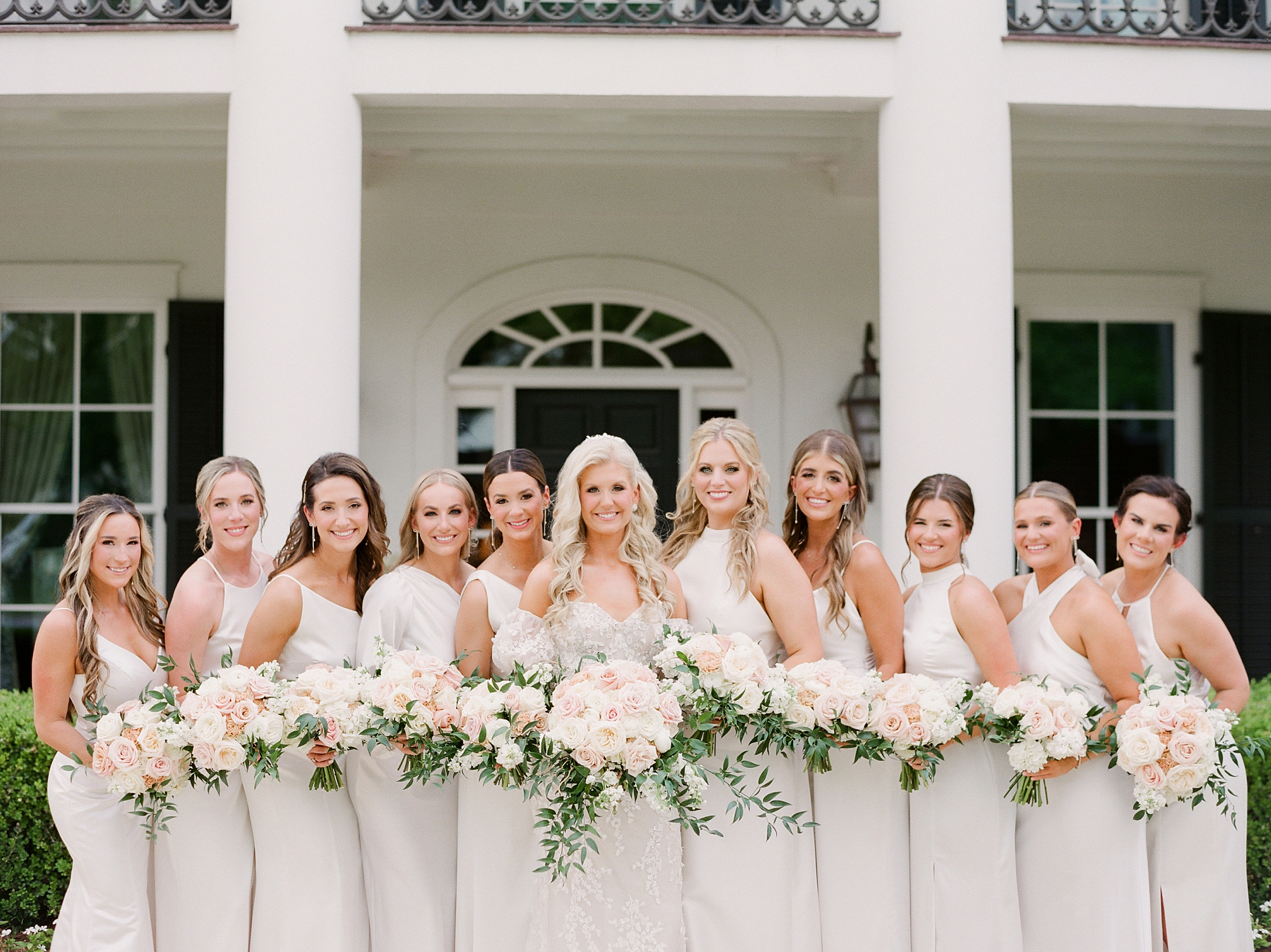 bride poses with bridesmaids in ivory gowns at the University of Louisiana at Lafayette