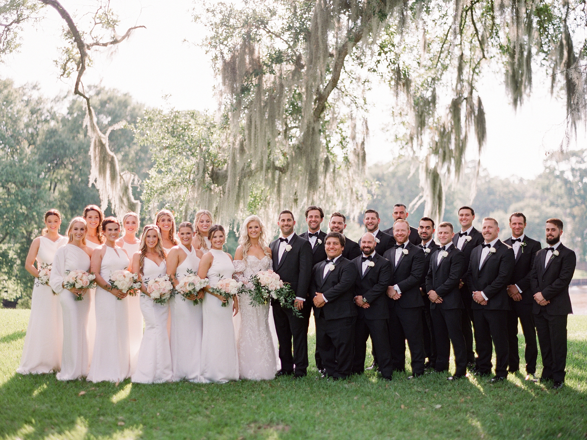 bride and groom pose with wedding party under Spanish moss at the University of Louisiana at Lafayette alumni center