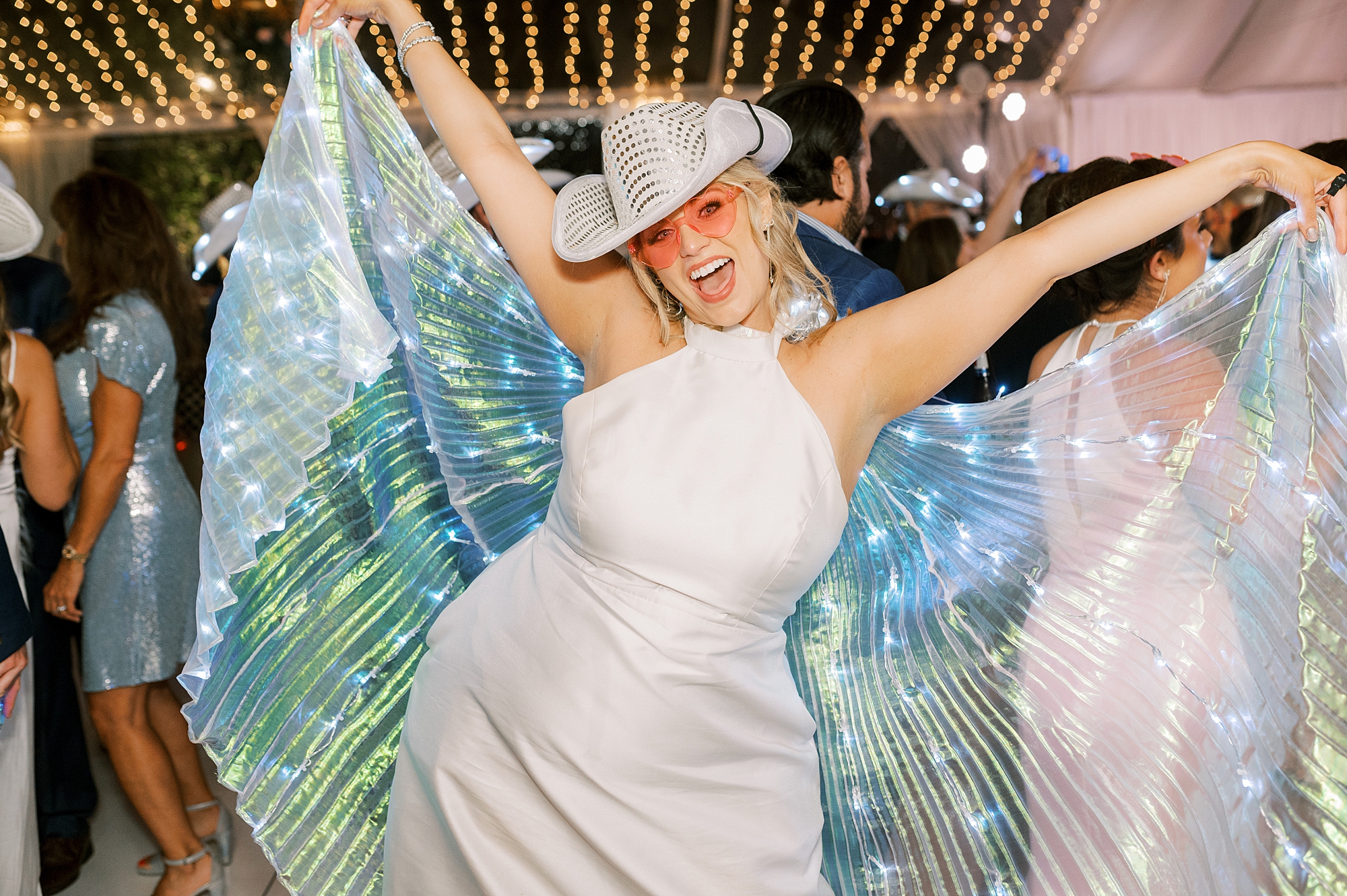 bridesmaid dances with fun cowboy hat and pink glasses 