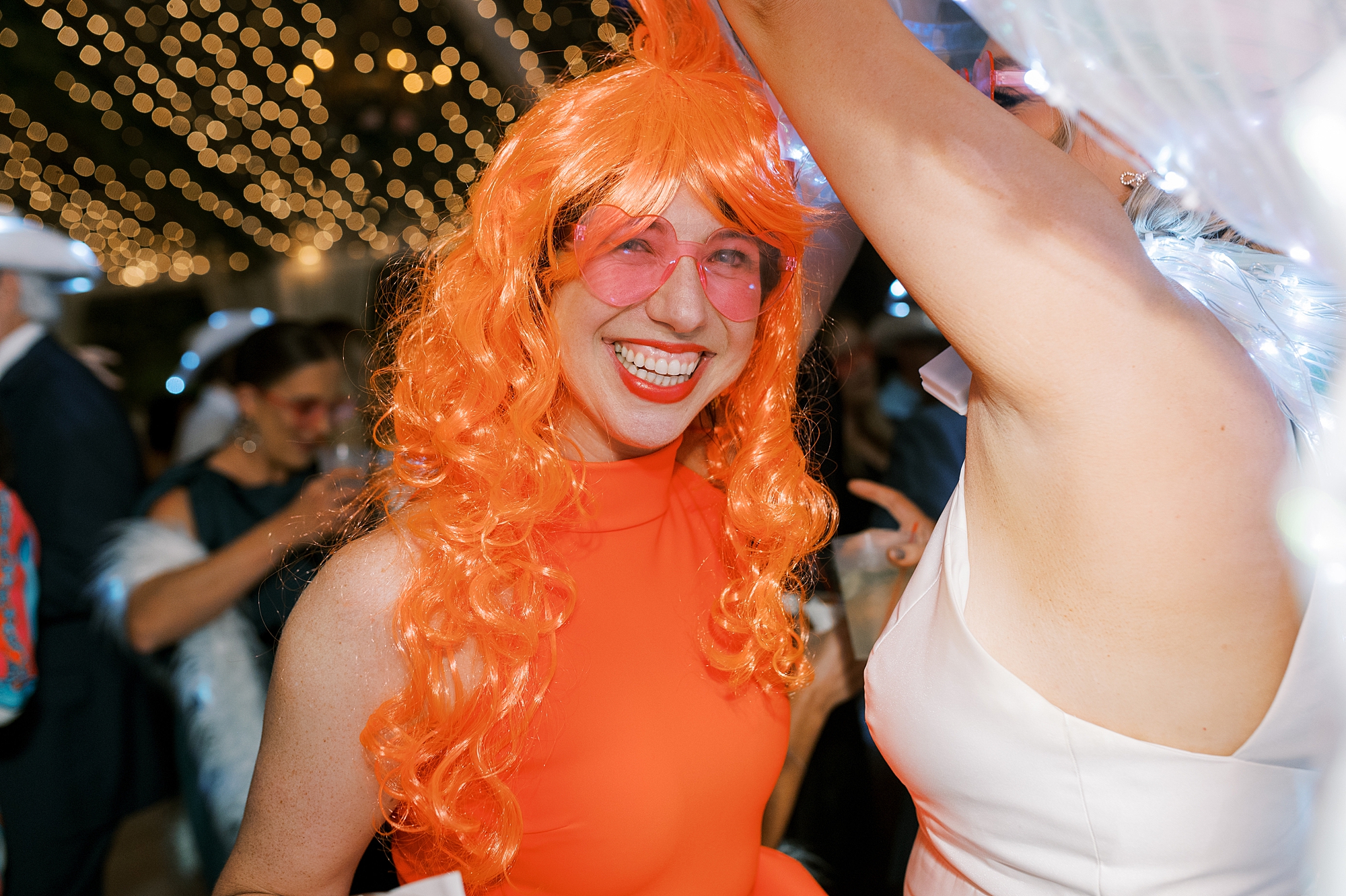guest dances in orange dress and wig at the University of Louisiana at Lafayette alumni center