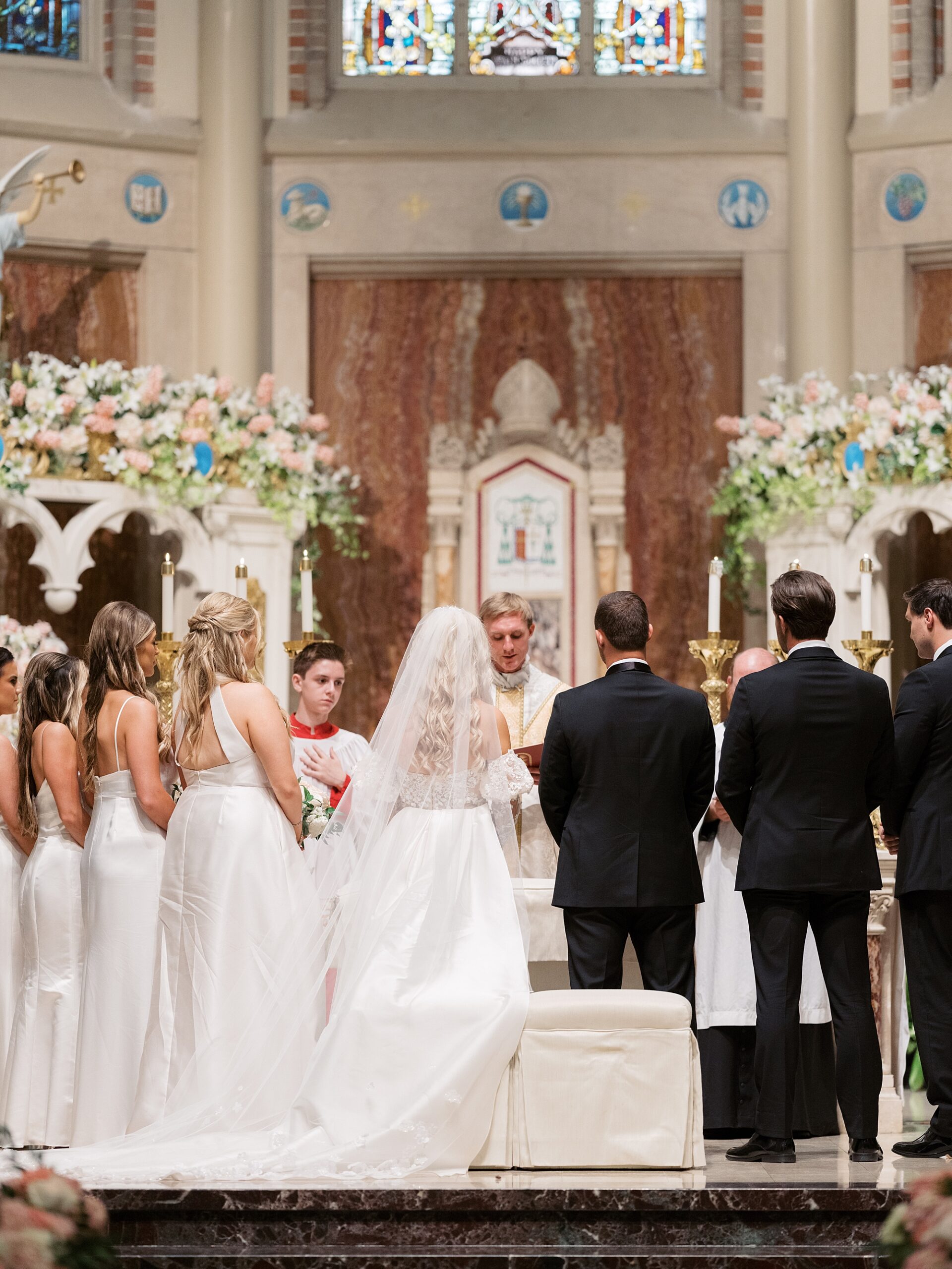 newlyweds stand at alter with wedding party for traditional ceremony at Cathedral of St. John