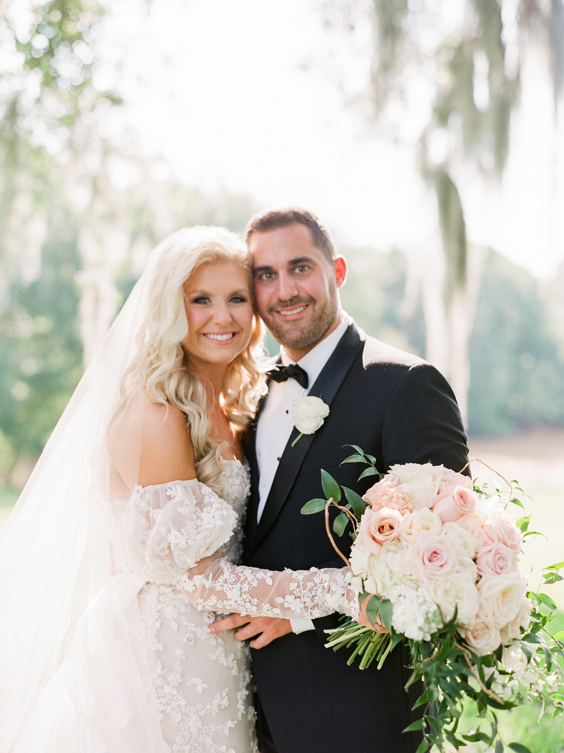 bride and groom hug under Spanish moss at the University of Louisiana at Lafayette alumni center