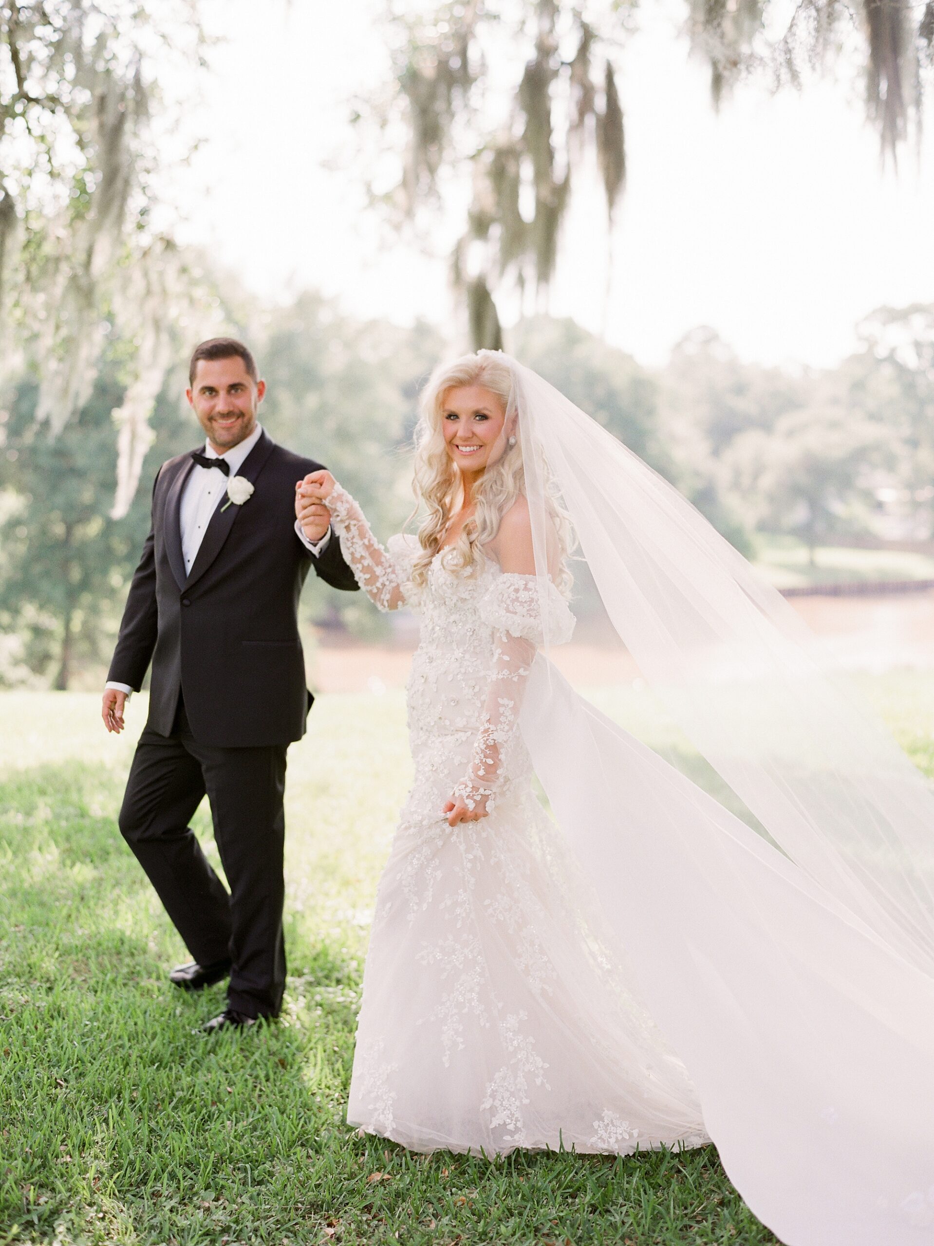 groom leads bride on lawn at the University of Louisiana at Lafayette alumni center