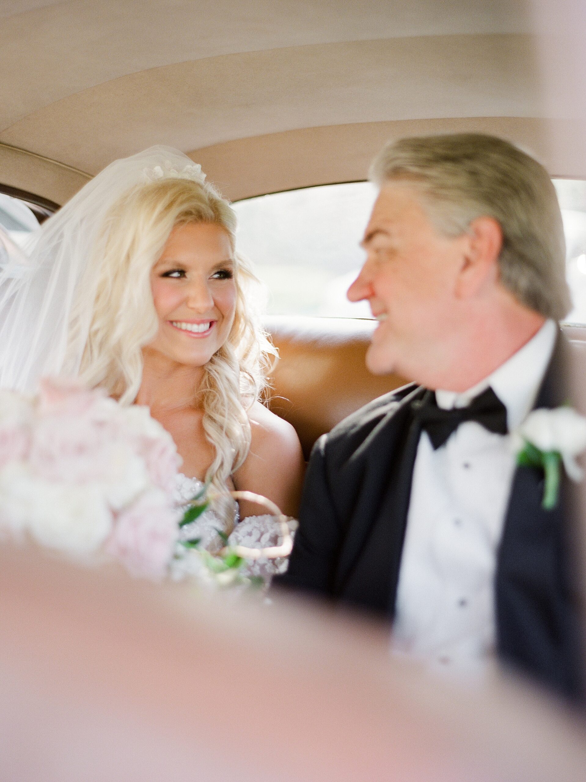 bride and father smile at each other in car before LA wedding day 