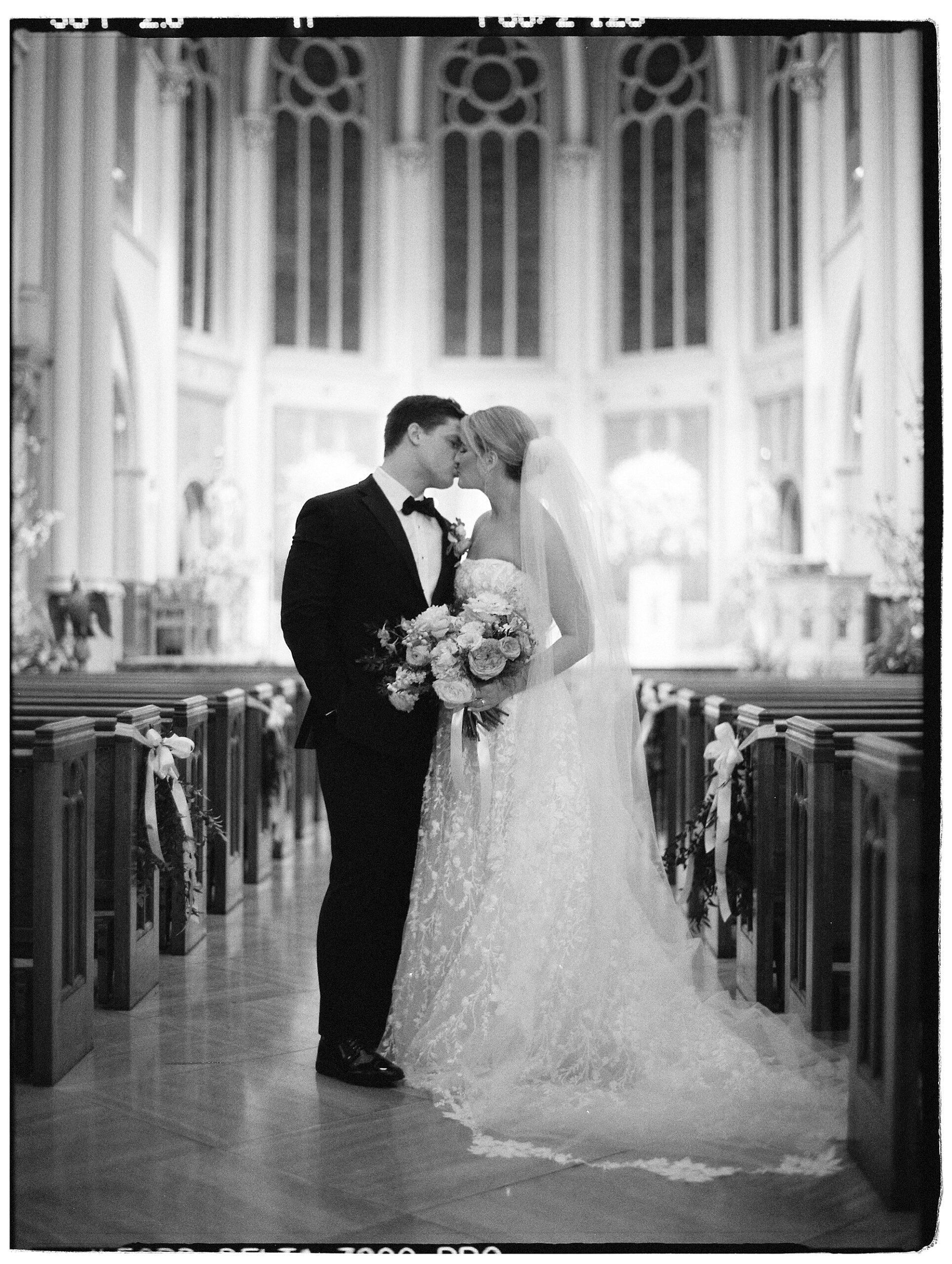 couple kisses in aisle of St. John’s Cathedral in New Orleans