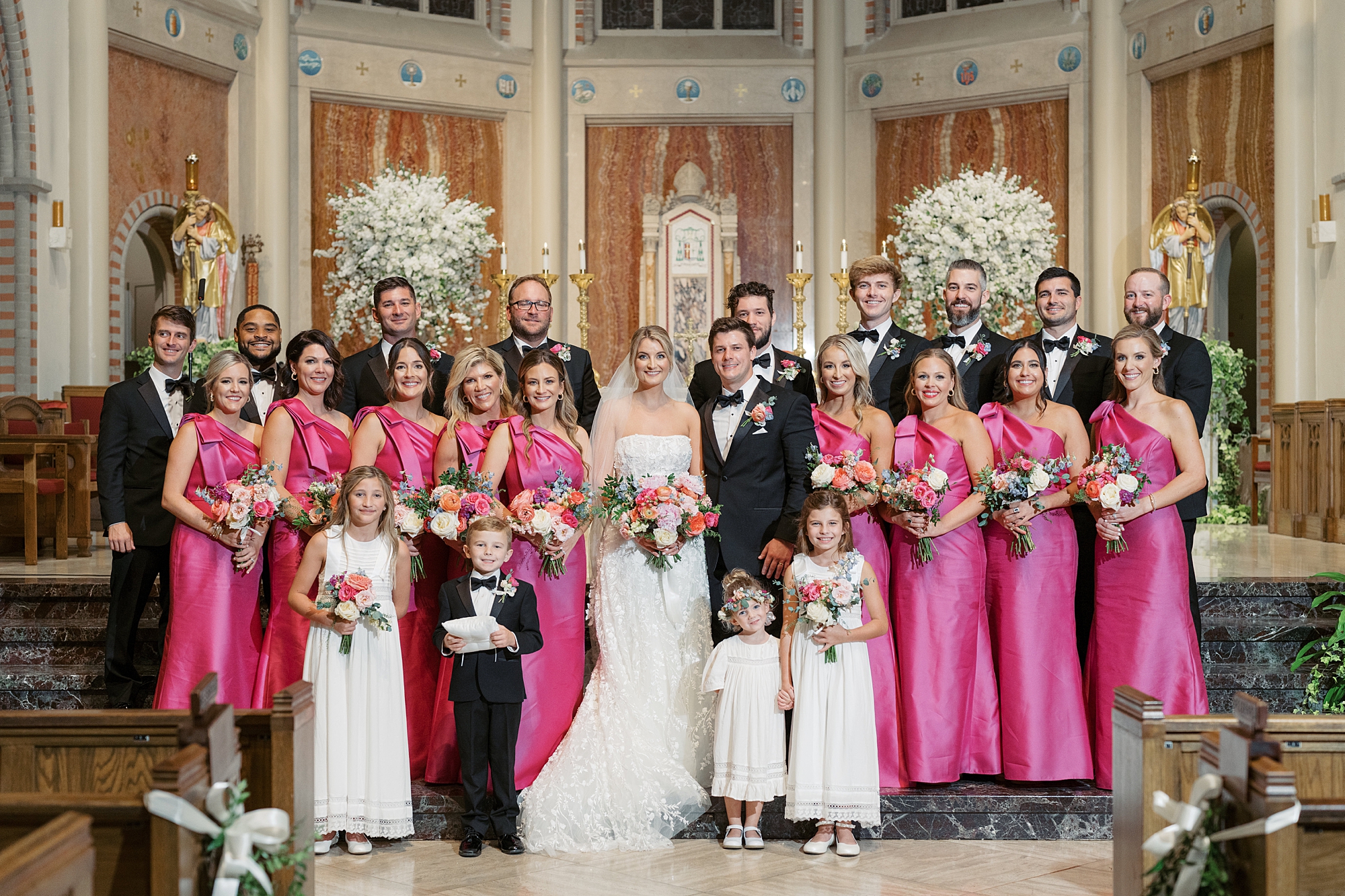 bride and groom pose with wedding party in pink and black inside the Cathedral of St. John the Evangelist
