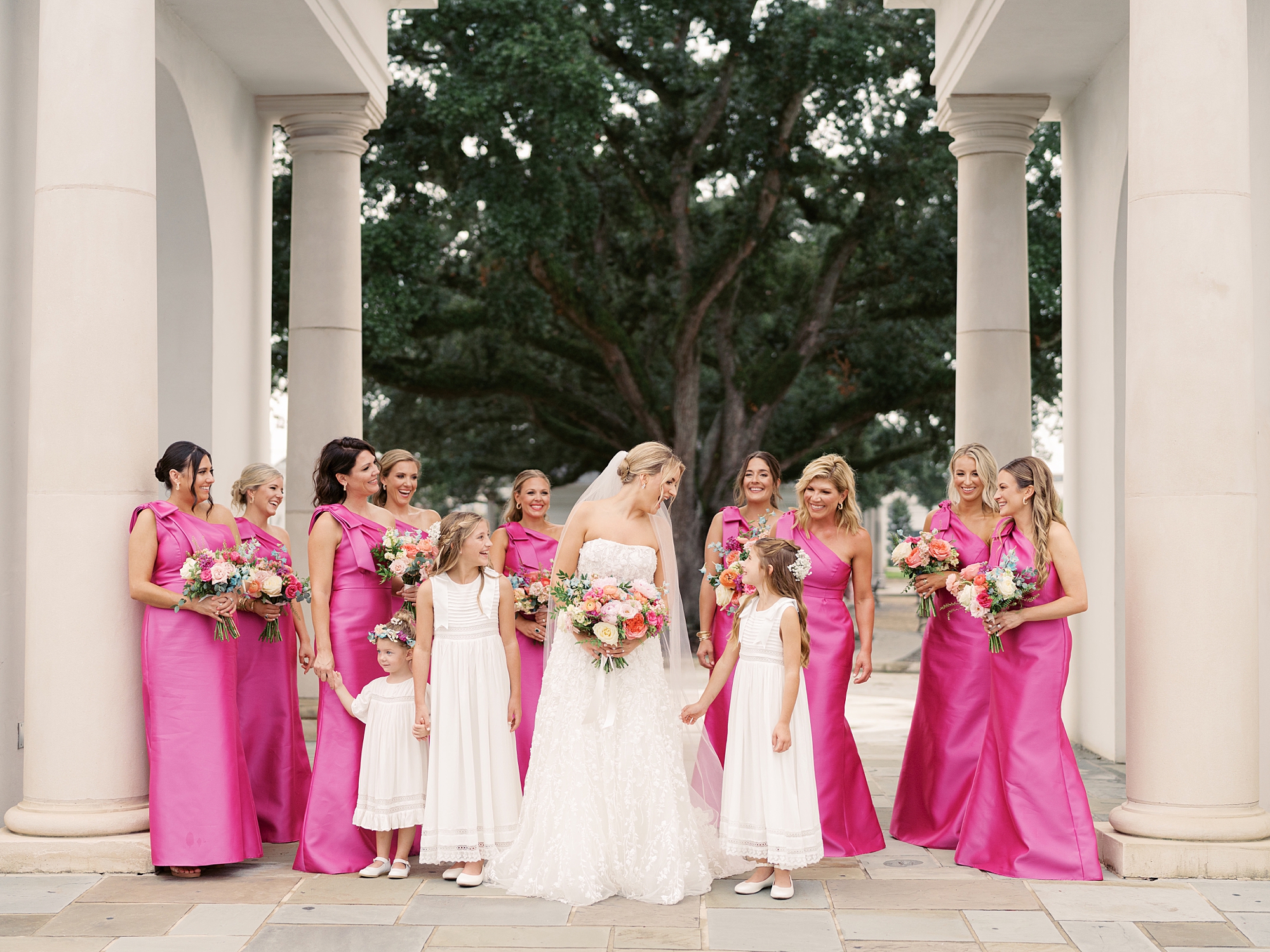 bride walks with bridesmaids in bright pink gowns in Lafayette LA