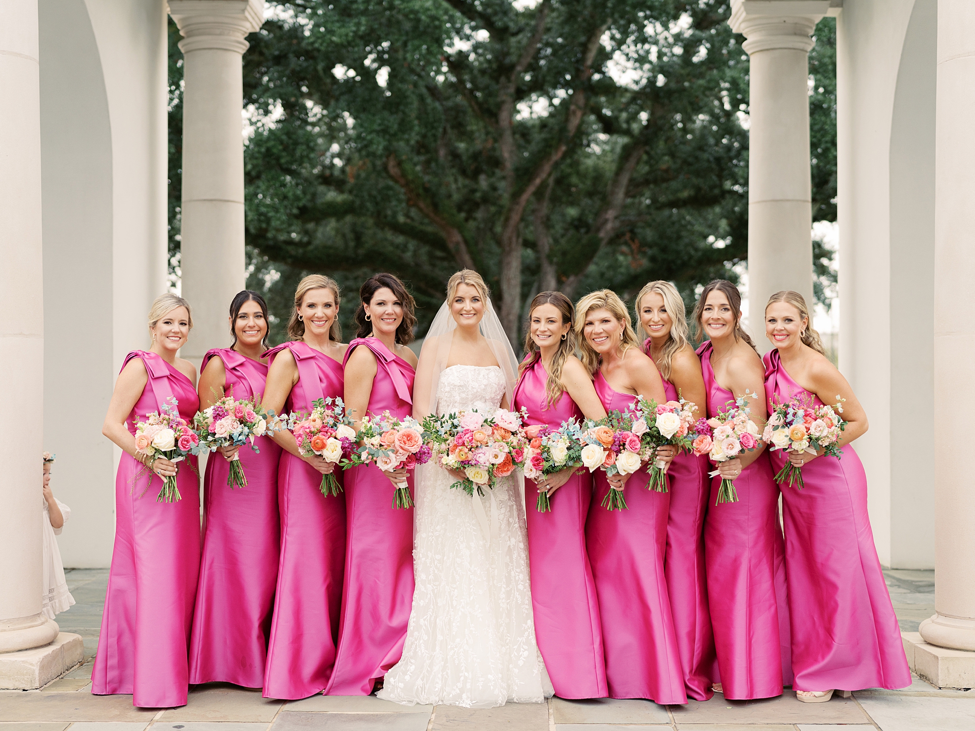 bride poses with bridesmaids in pink gowns during Louisiana wedding 
