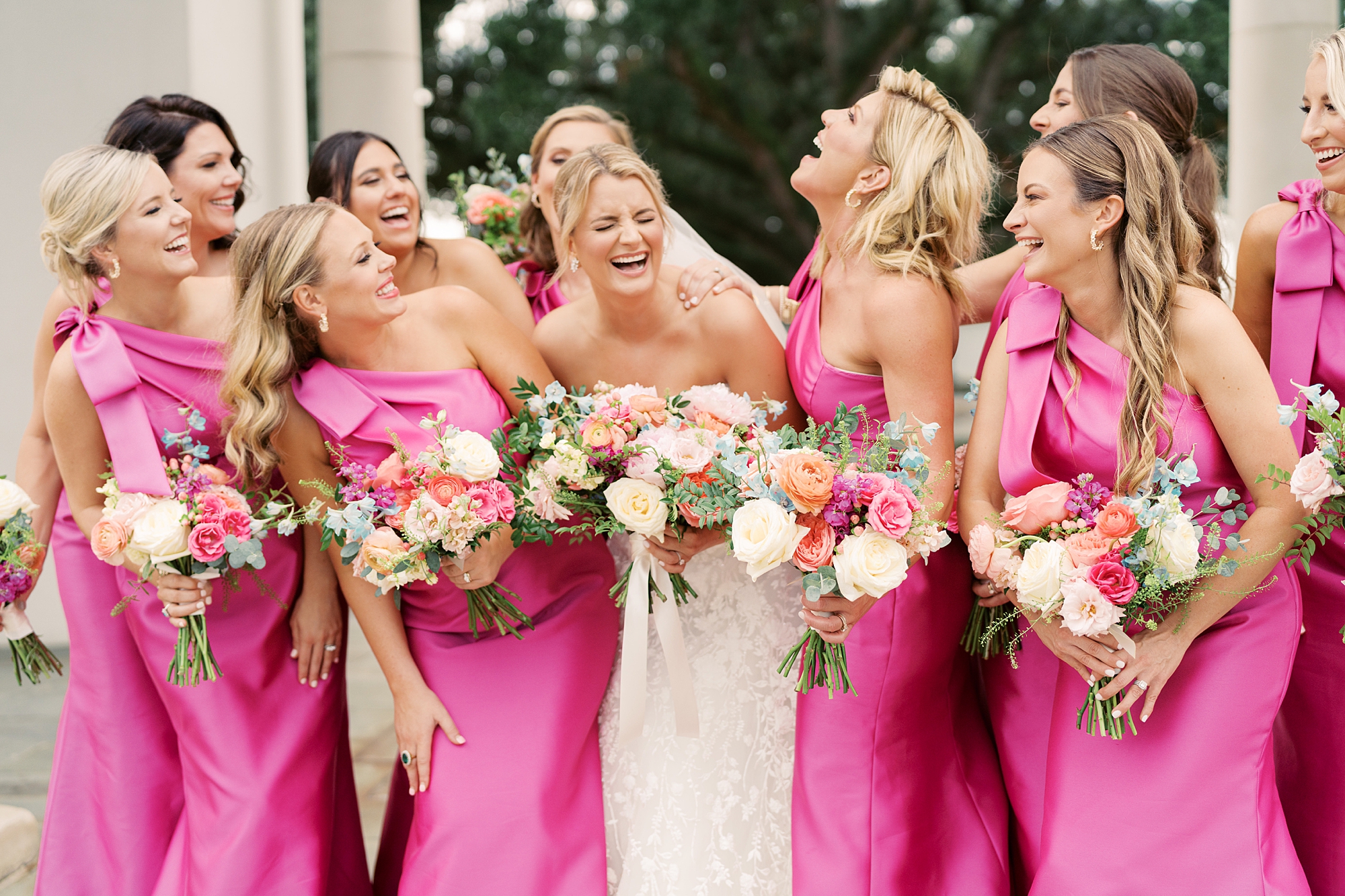 bride and bridesmaids in pink gowns laugh during wedding day in Lafayette LA