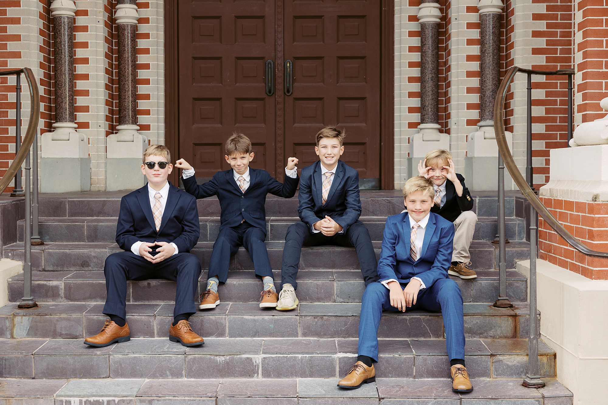 ring bearers and young children sit on steps outside the Cathedral of St. John the Evangelist