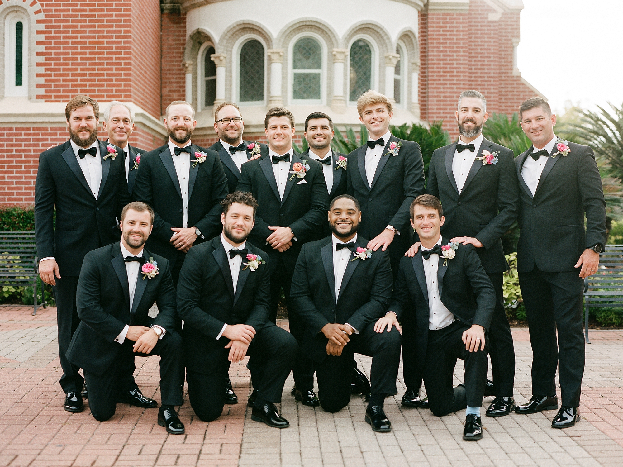 groom stands with groomsmen around him outside the Cathedral of St. John the Evangelist