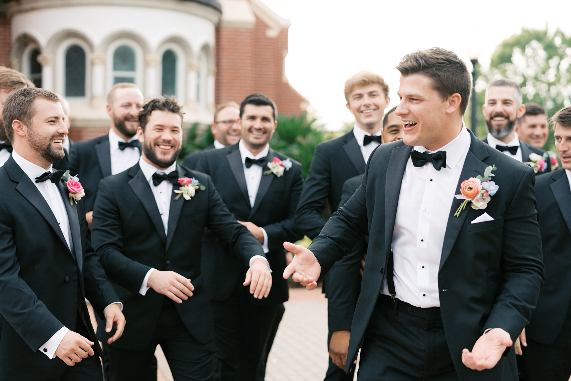 groom and groomsmen laugh together outside the Cathedral of St. John the Evangelist