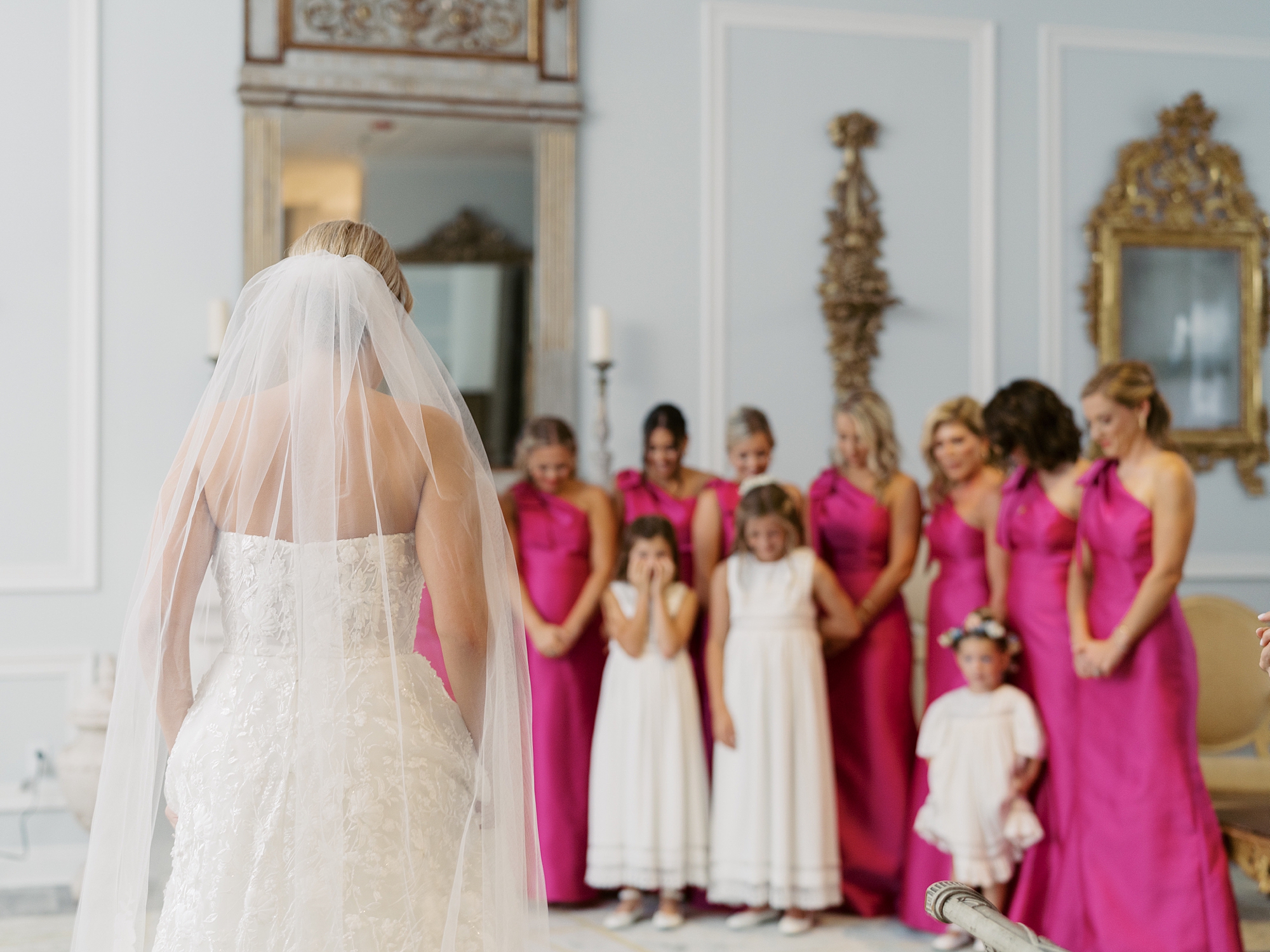 bride shows off gown and veil to bridesmaids in suite at Le Pavilion Hotel