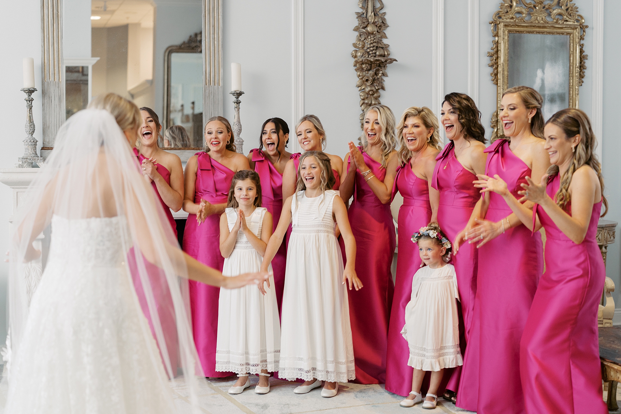 bridesmaids and flower girls cheer for bride during first look 