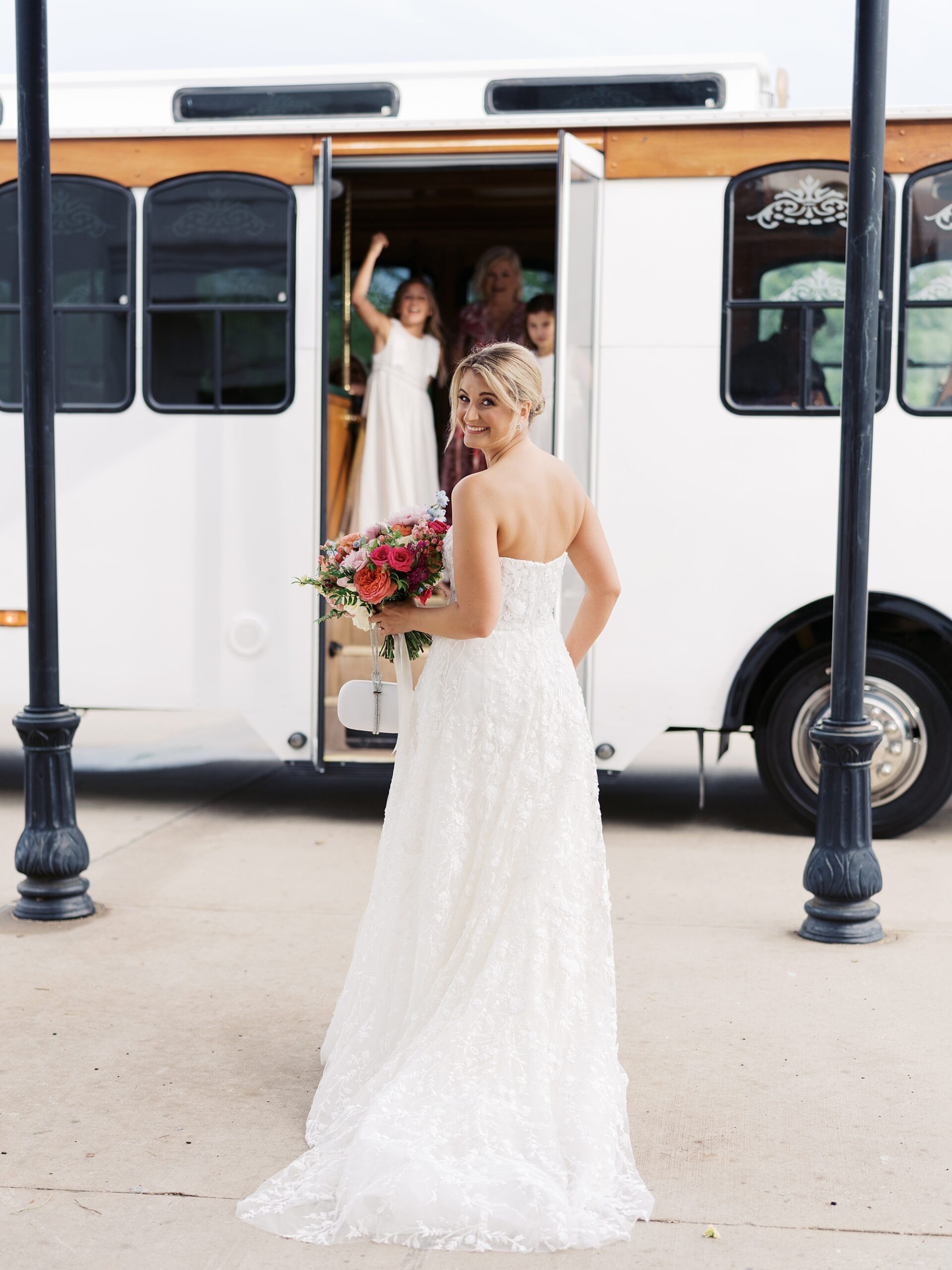 bride looks over shoulder walking to white trolley in Lafayette LA