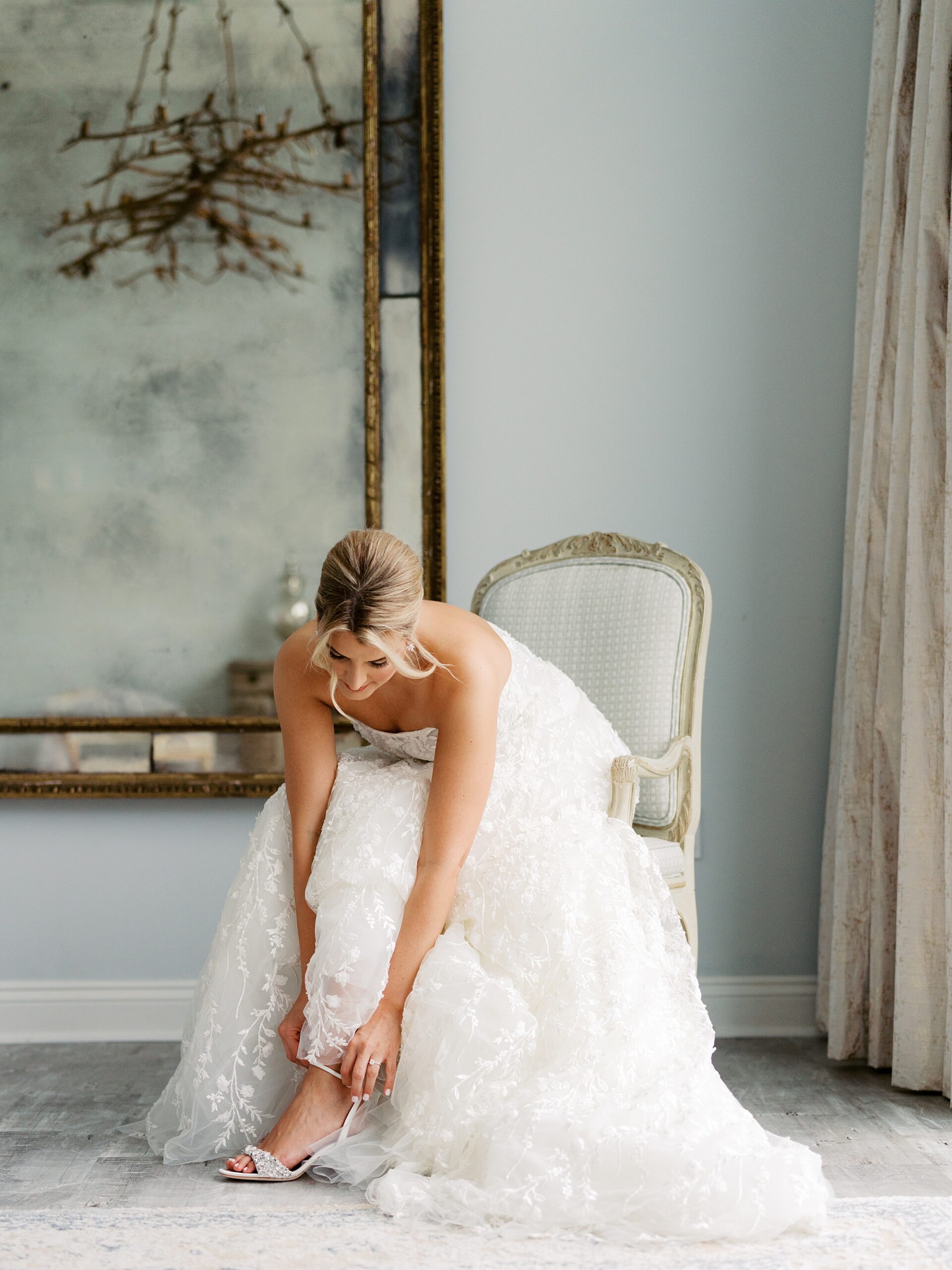 bride leans down to adjust shoes under skirt of wedding dress at Le Pavilion Hotel