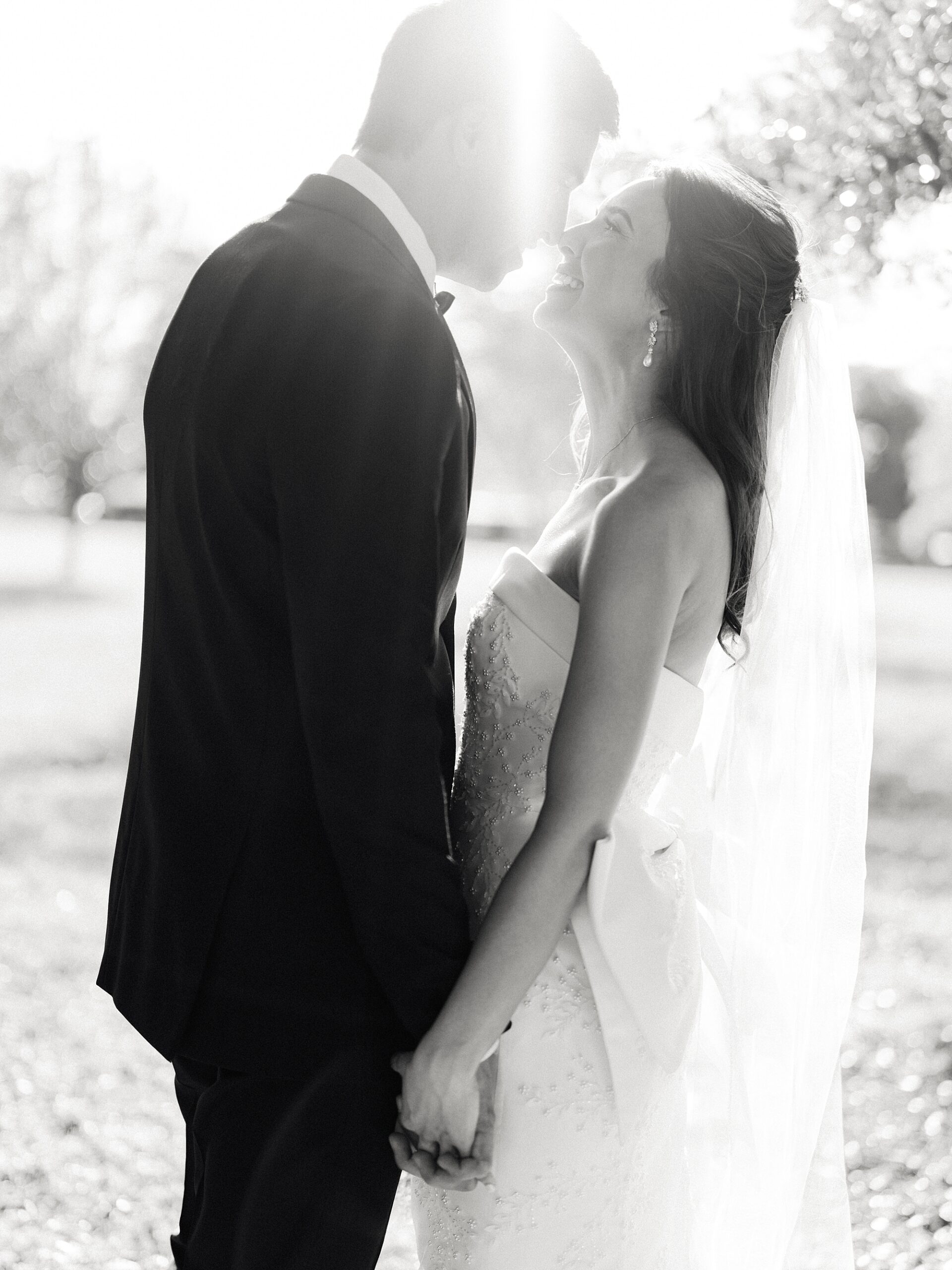 black and white photo of bride and groom leaning to kiss