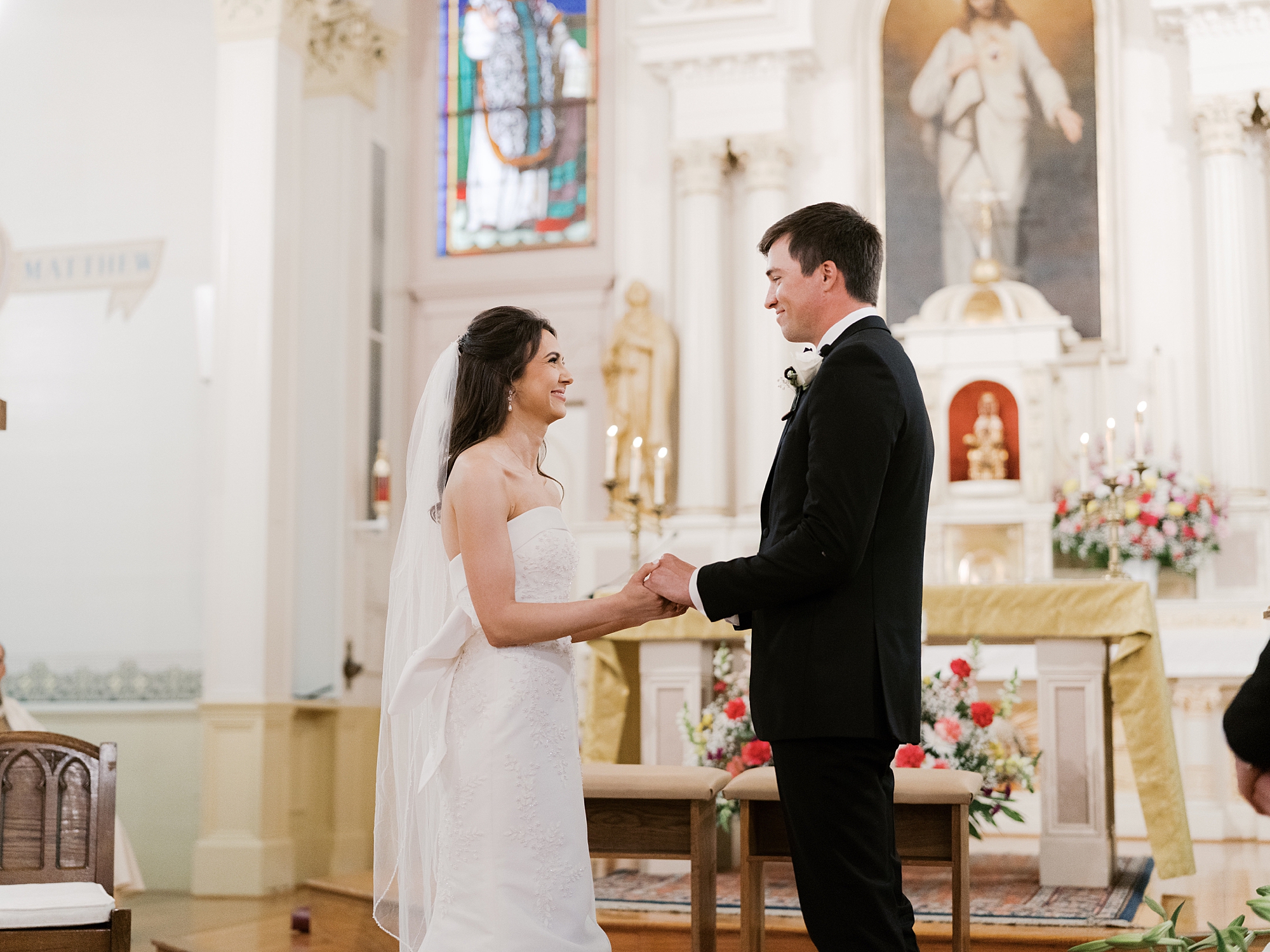 bride and groom stand together during traditional catholic wedding ceremony inside St. Charles Borromeo