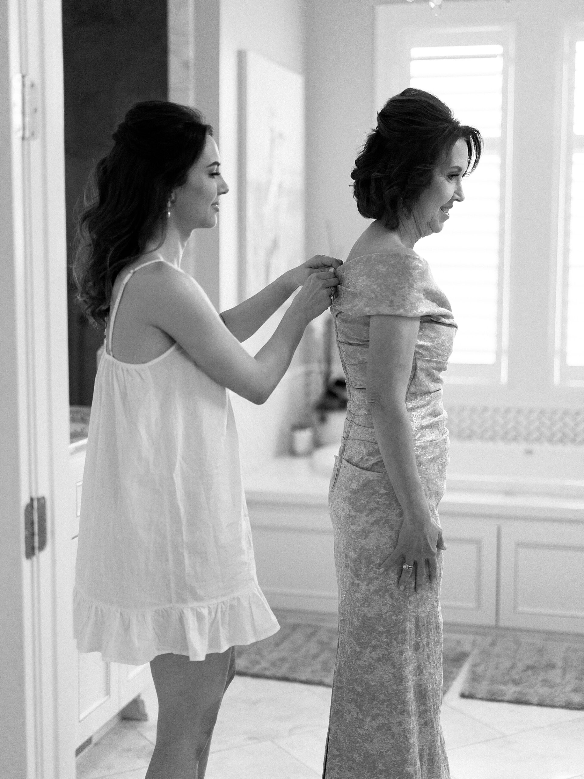bride helps mother into dress for Lafayette LA wedding day