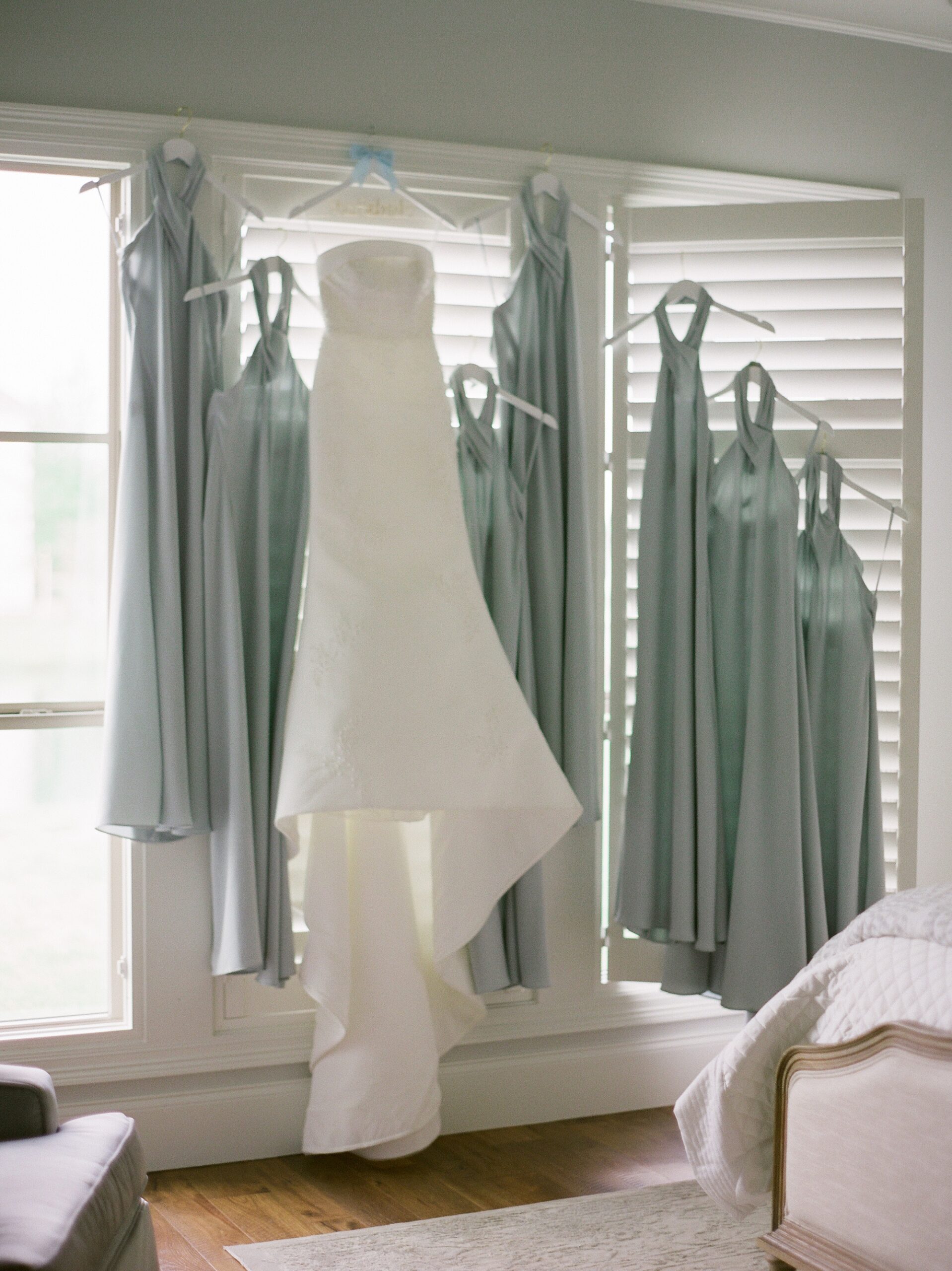 wedding dress and green gowns hang in window of Lafayette LA hotel