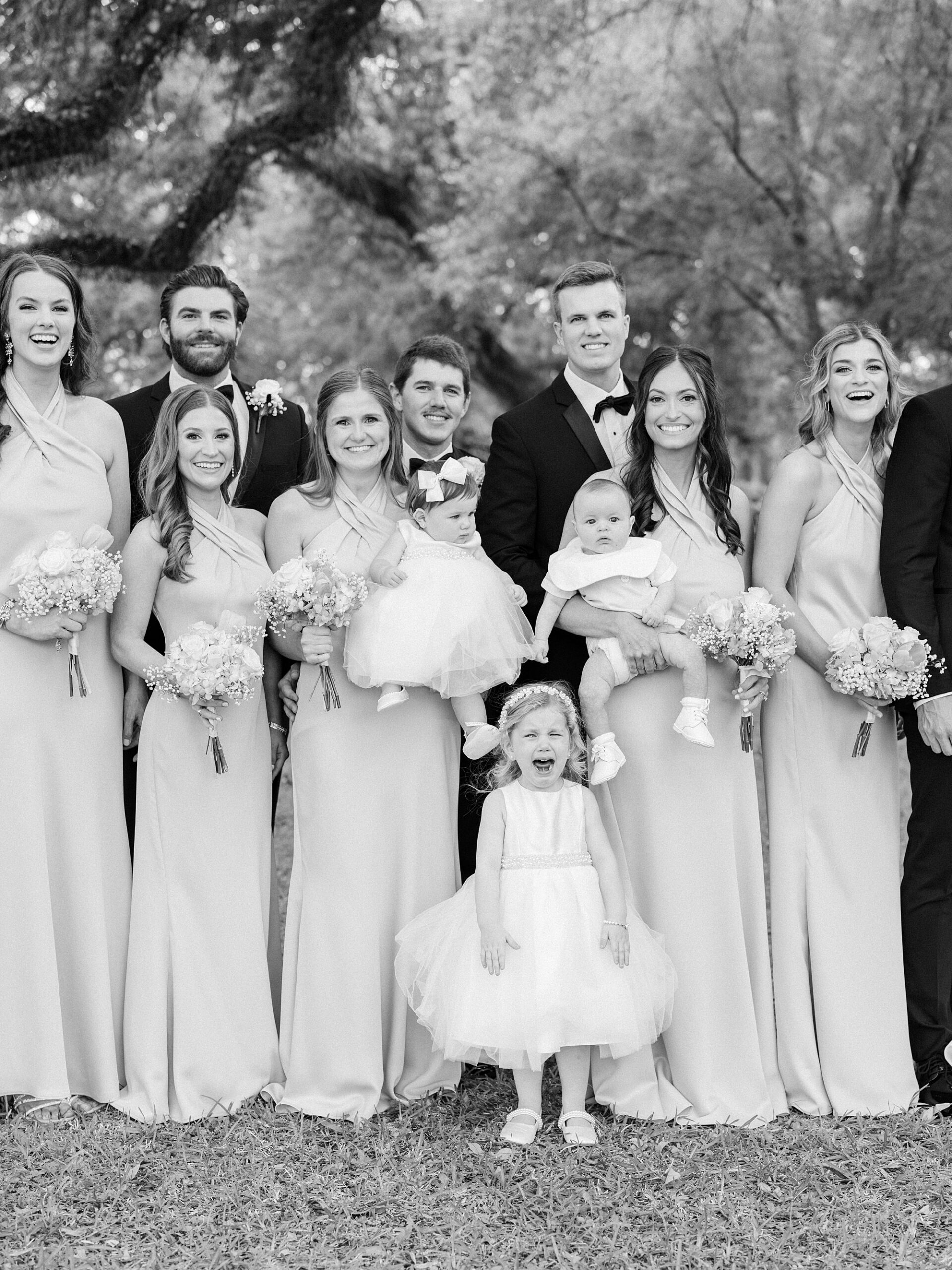 newlyweds pose with wedding party including small flower girls