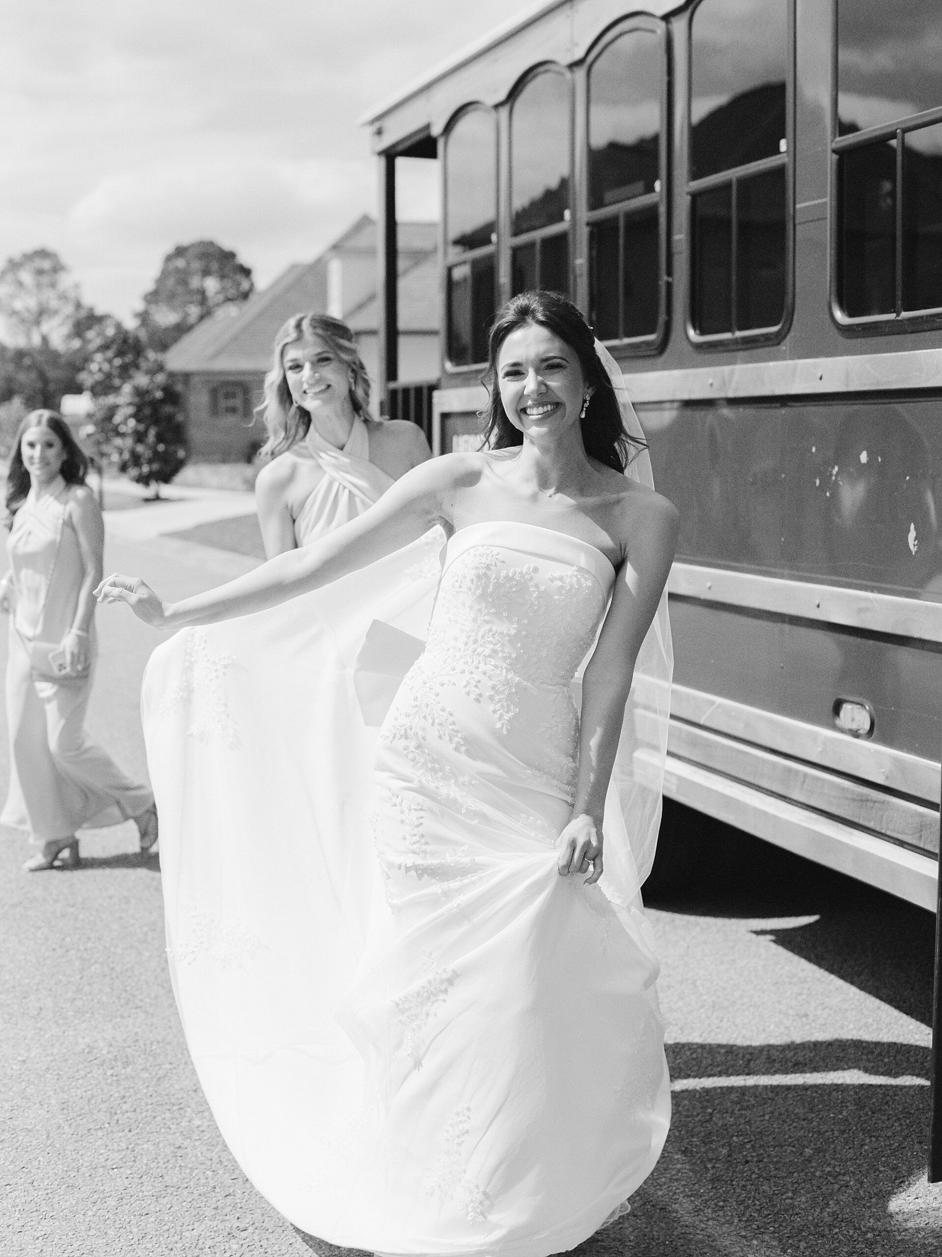 bride holds out skirt of wedding gown by trolley during Lafayette LA wedding day