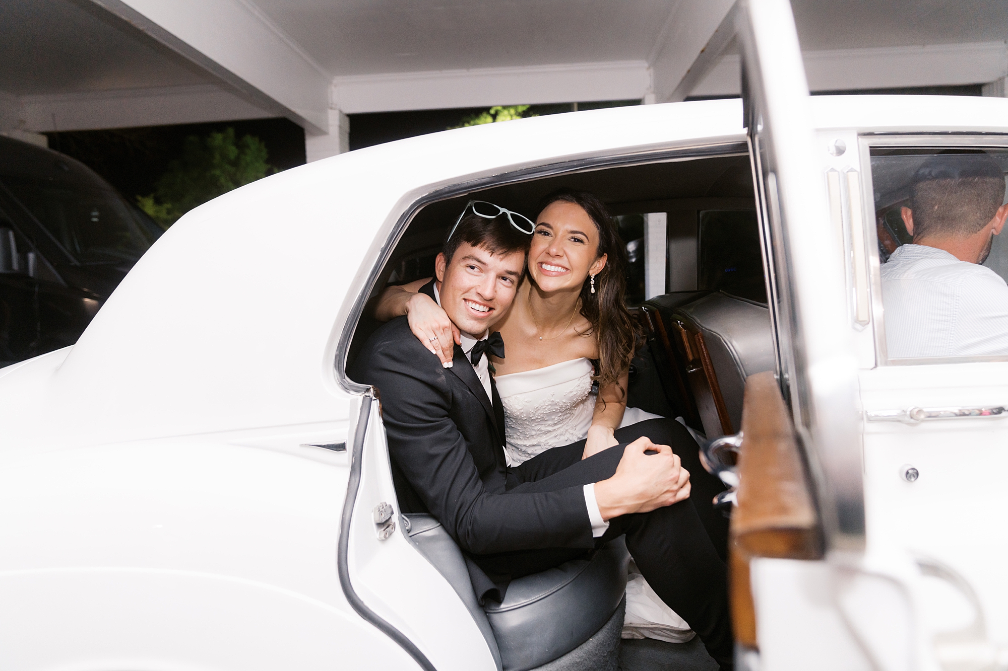 bride and groom hug in white classic car leaving LA reception