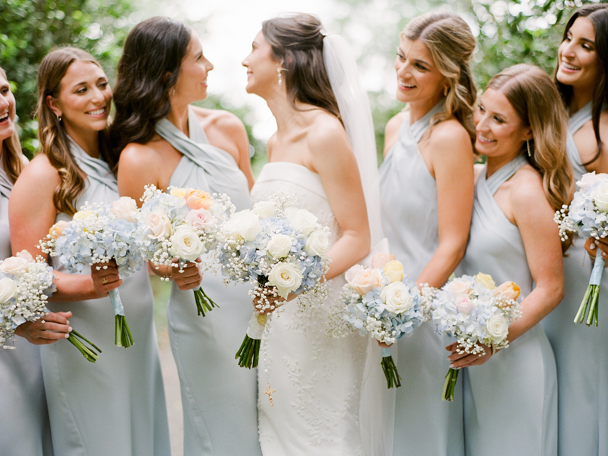 bride smiles at bridesmaids in pale green gowns in Lafayette LA