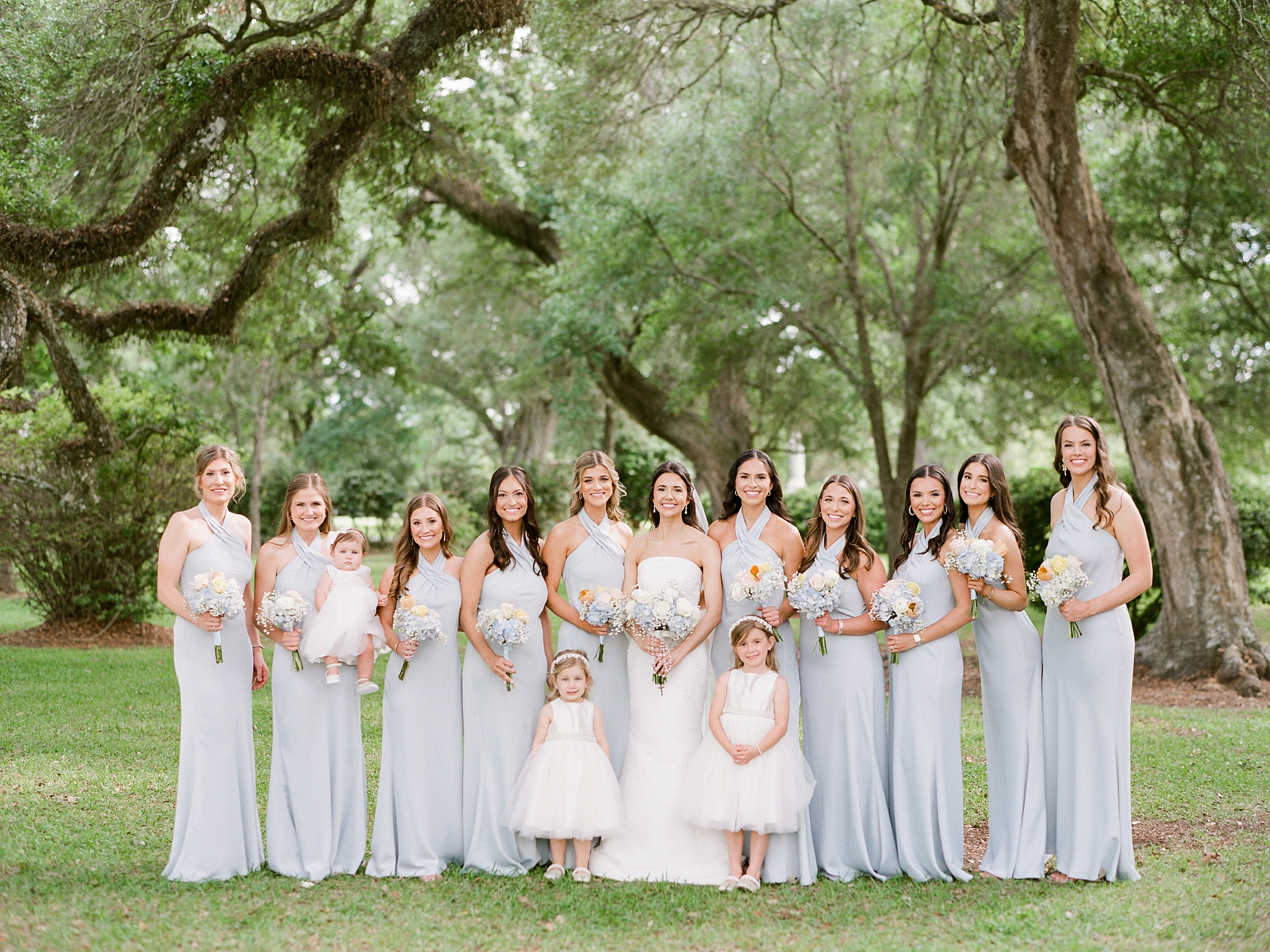 bride stands with bridesmaids in pale green gowns outside St. Charles Borromeo