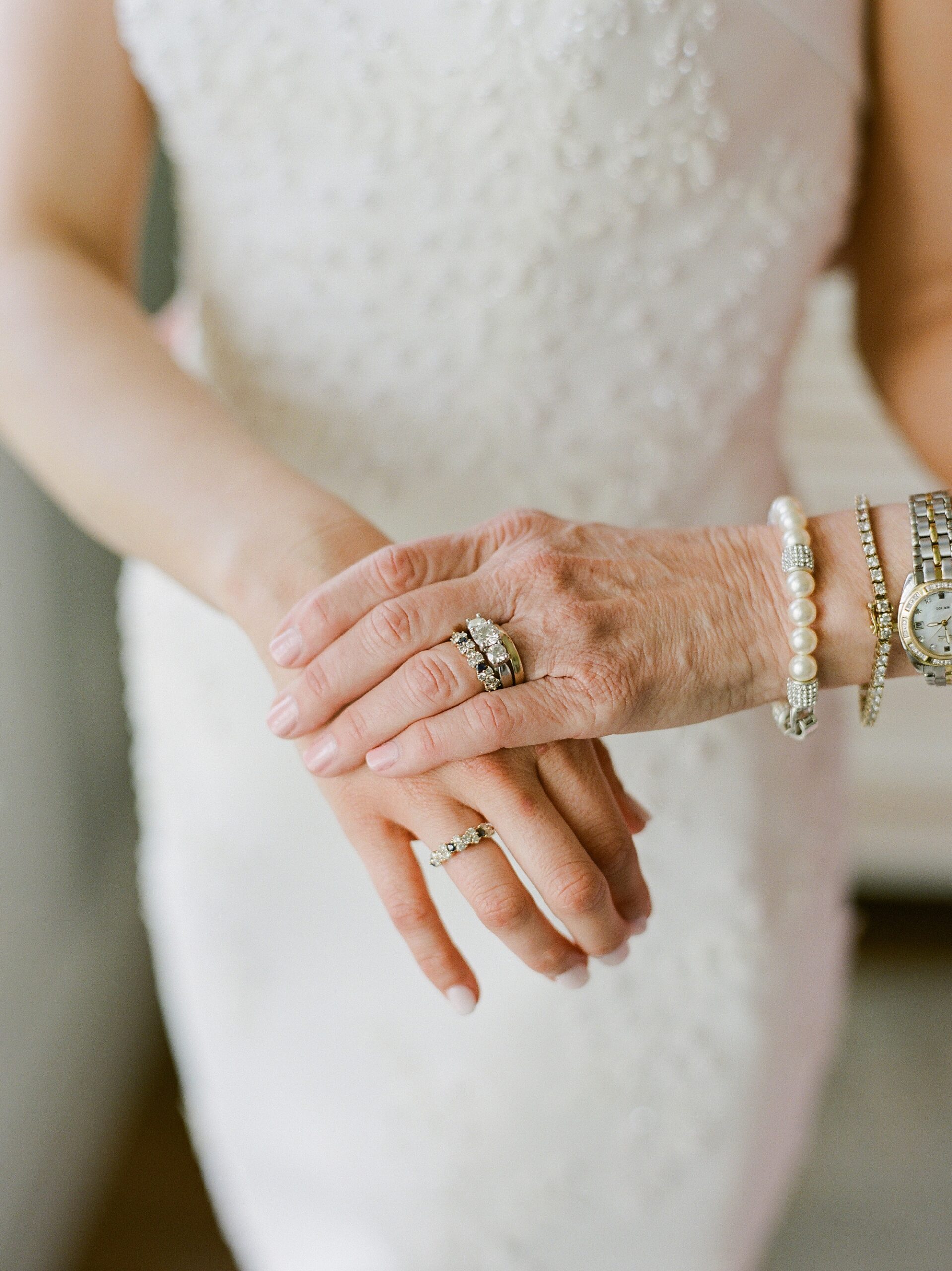 bride stands holding hands with grandmother showing off rings
