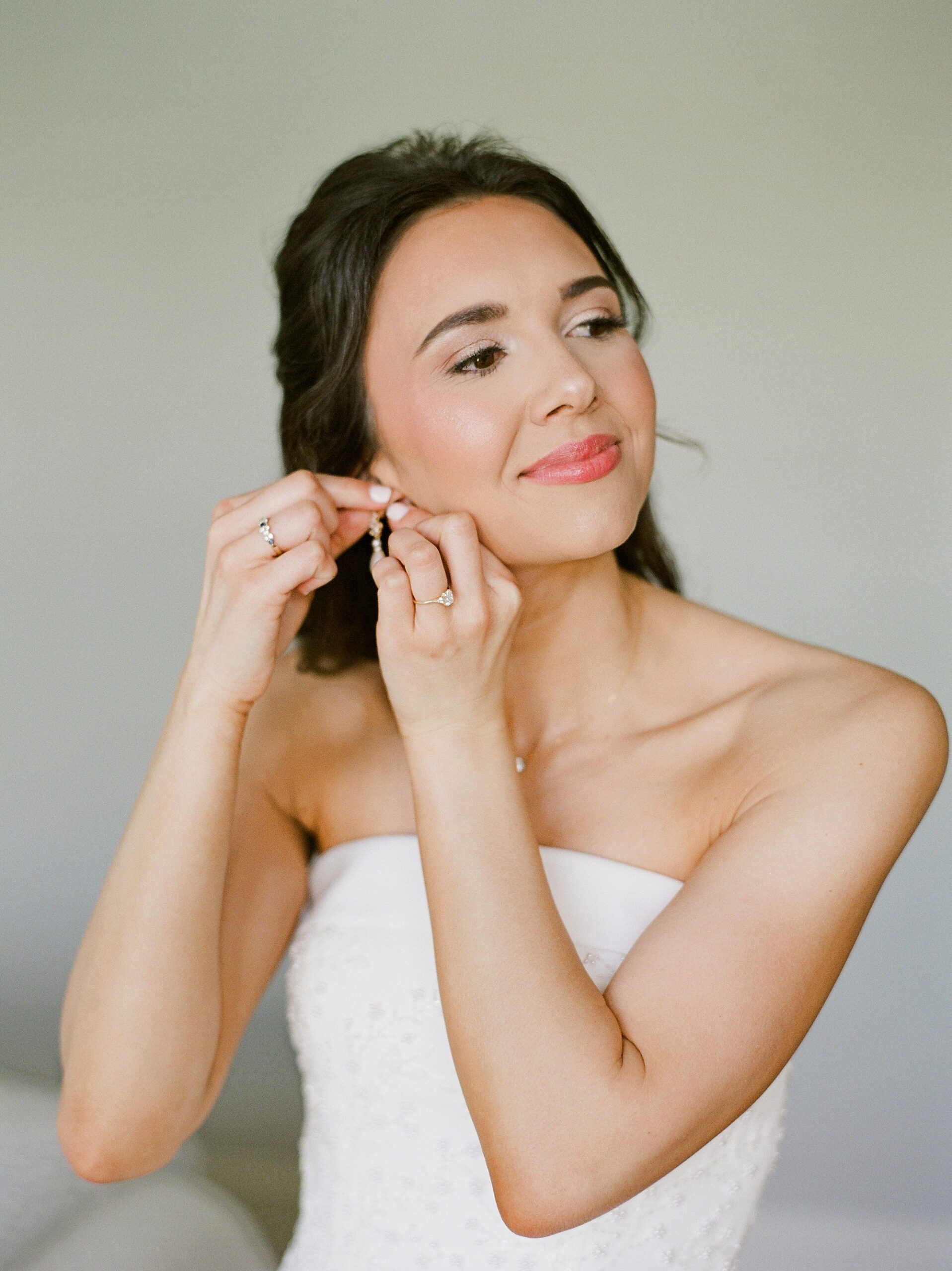 bride puts on earrings before Lafayette Louisiana wedding day
